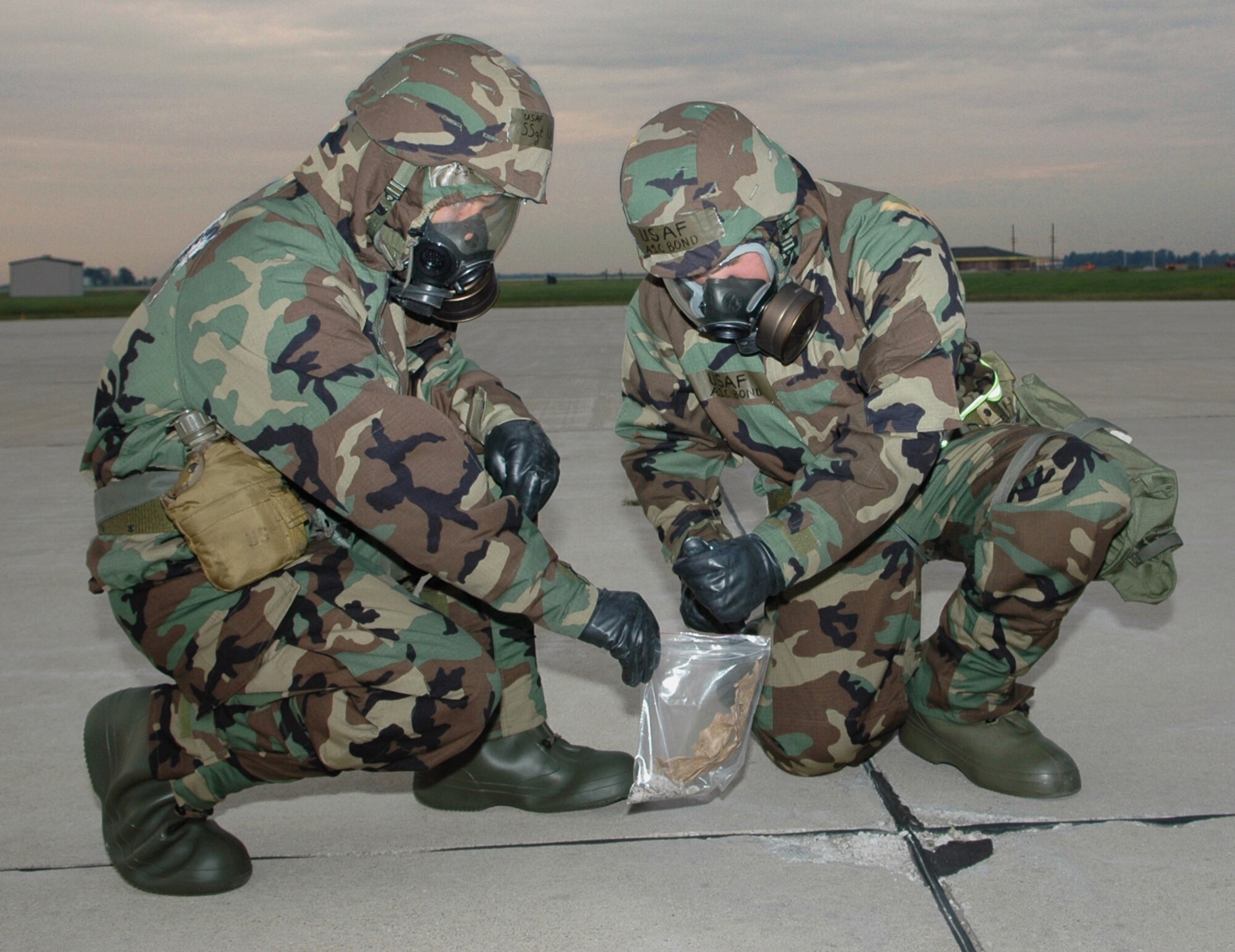 GRISSOM AIR RESERVE BASE, Ind., -- Staff Sgt. Zuriel Lund, left,  and Airman Benjamin Bond, both crew chiefs with the 434th Aircraft Maintenance Squadron, gather foreign objects and debris during an inspection of the mass parking ramp.   The Airmen wore the highest level of chemical protection during an exercise to ensure they are comfortable wearing the gear and operating in chemical or biological threat environments.   (U.S. Air Force photo/Senior Airman Ben Mota)