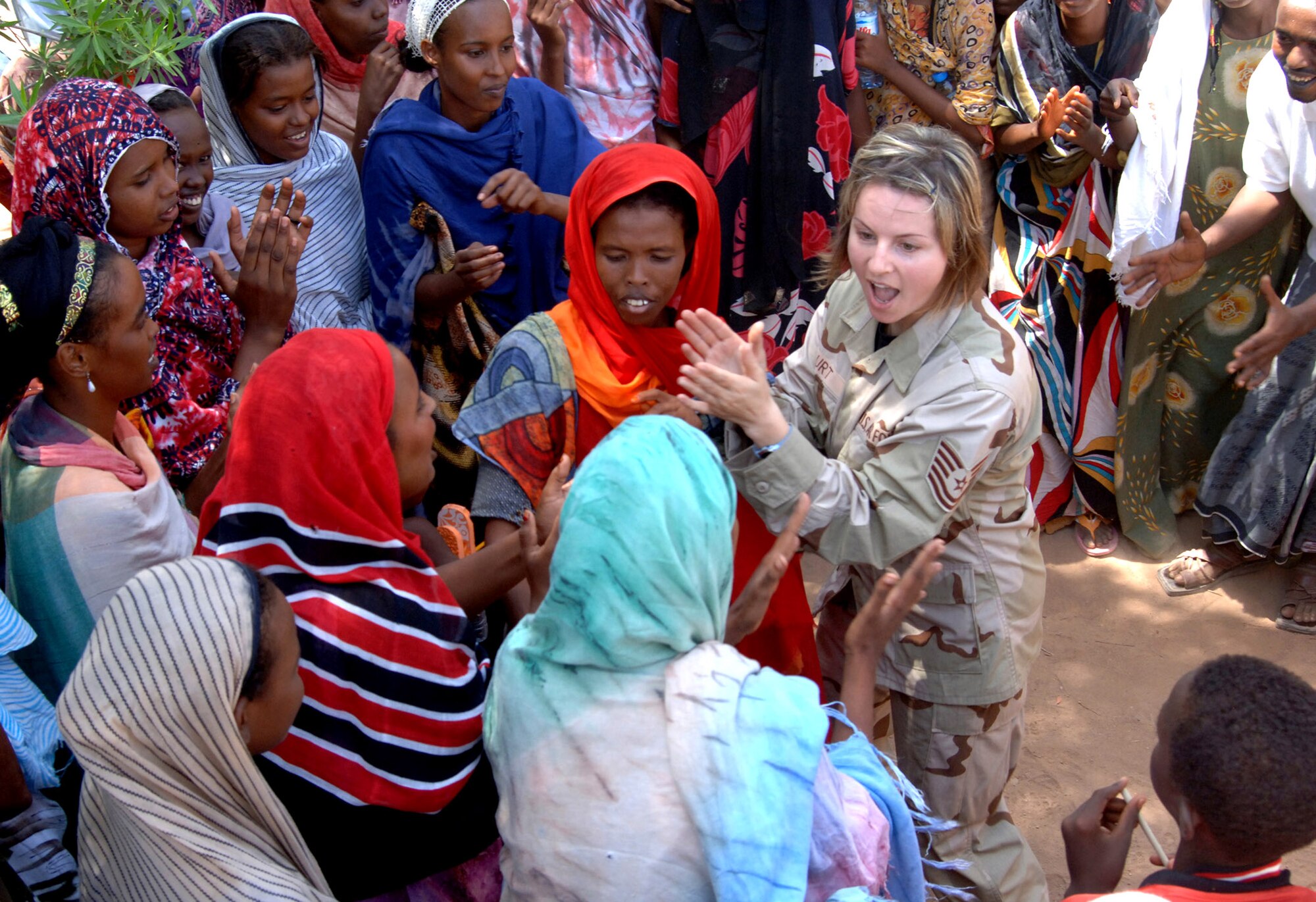 Tech. Sgt. Sherry Burt dances and sings with locals from the village of Damerjog, Djibouti after performing with the U. S. Central Command Air Forces Expeditionary Band the "Desert Ramblers," for the locals Oct. 9. Sergeant Burt is a vocalist and Irish flute player. The band was in the area for a tour stop at Camp Lemonier, Djibouti. (U.S. Navy photo/Navy Petty Officer 2nd Class Regina L. Brown) 