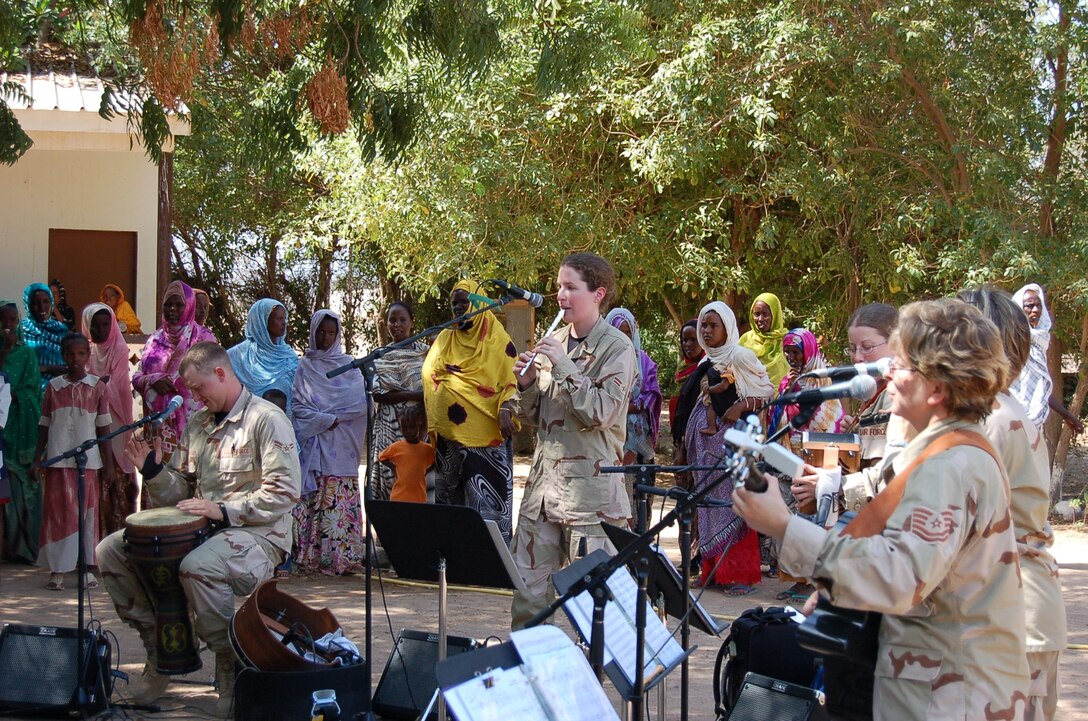 (L-R) Airman 1st Class Brandon Richard (Percussion), Airman 1st Class Amy McCann (Whistle), Staff Sergeant Lacey Stokes (Accordion), Technical Sergeant Gail Adams (Guitar) and Technical Sergeant Sherry Burt (obscured)  of the USAF Heritage of America Band's Heritage Aire Celtic music ensemble perform for local residents of Damerjog, Djibouti while on deployment with the US Central Command Air Force (CENTAF) Band's Desert Ramblers.
