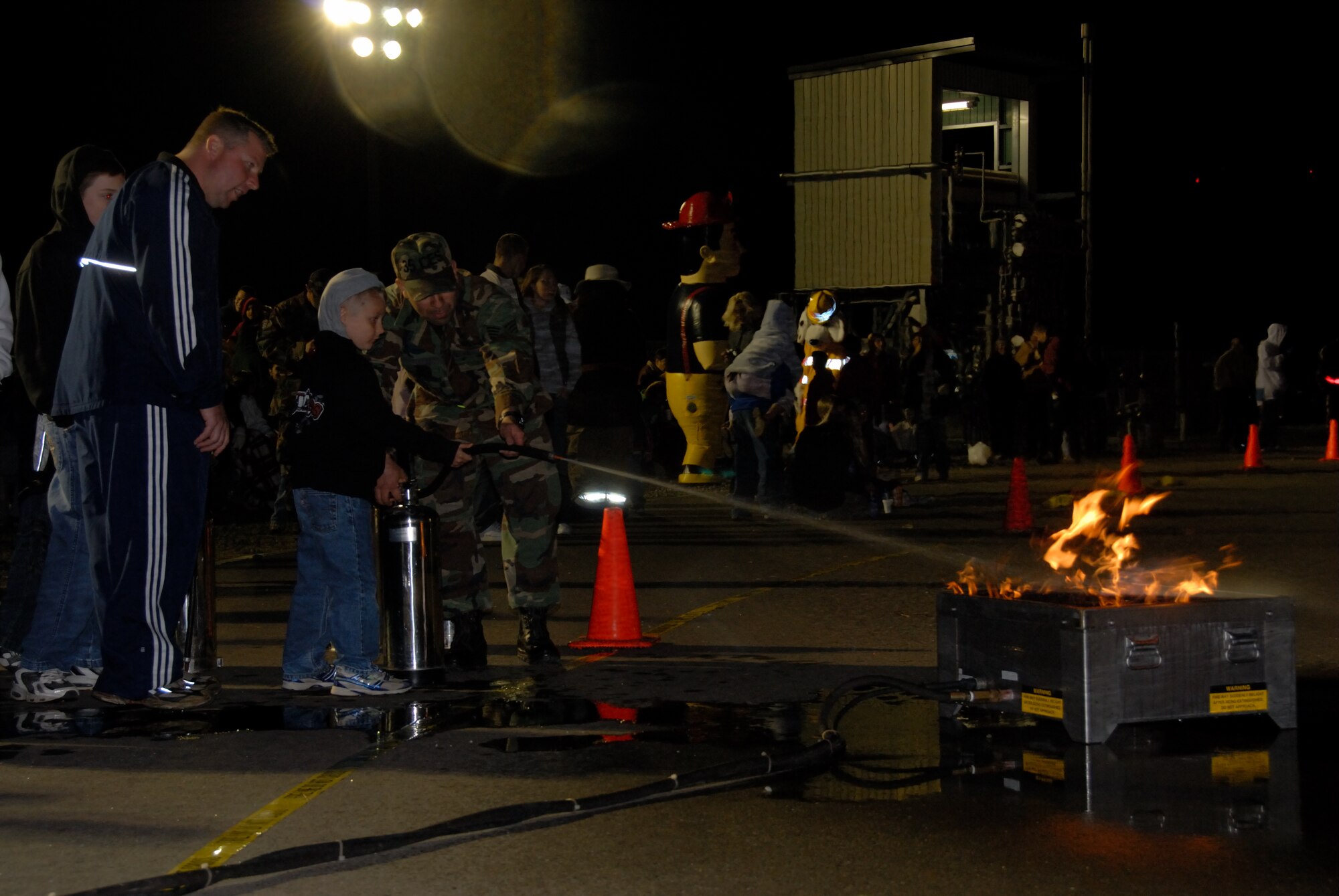 MISAWA AIR BASE, Japan -- Senior Chief Petty Officer Joseph Varcasia, from the Aircraft Intermediate Maintenance Detachment, and his son Douglass are shown how to properly use a fire extinguisher by Staff Sgt. Andres Steevens from the 35th Civil Engineering Squadron during fire prevention week here on Oct. 9, 2007.  The 35th Civil Engineering Squadron annually demonstrates fire fighting procedures for Misawa residents.  (U.S. Air Force photo by Senior Airman Laura R. McFarlane)(RELEASED)