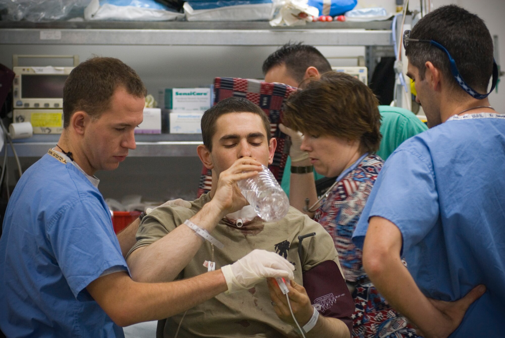 BALAD AIR BASE, Iraq -- Airman 1st Class Michael Brady, 732nd Air Expeditionary Group combat cameraman, sips water while being assessed upon arrival at the Air Force Theater Hospital here Oct 14. Airman Brady was transferred from the 28th Combat Support Hospital in Baghdad.  He was augmenting the Army in a non-traditional "in-lieu-of" tasking when he was wounded by sniper fire while on patrol in Ad Diwaniyah, Iraq. He is deployed from the 30th Space Communications Squadron, Vandenberg Air Force Base, Calif. (U.S. Air Force photo/Master Sgt. John Nimmo, Sr.)