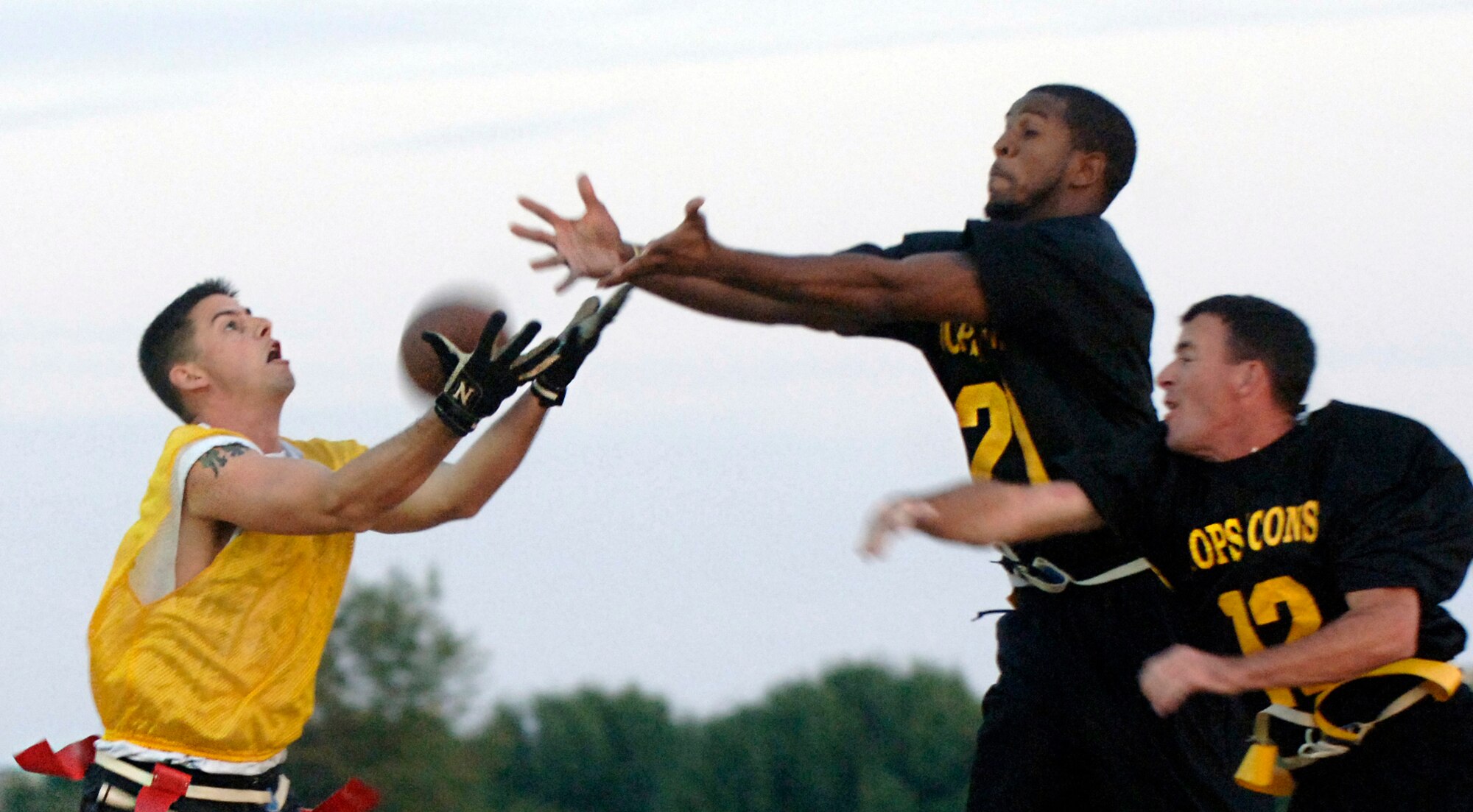LANGLEY AIR FORCE BASE, Va. -- Brooks Espy of the 1st Equipment Maintenance Squadron catches the first touchdown pass of the flag footgball game Oct. 15 despite the hands of Leonard Smith (top) and Bob Heiden of the 1st Security Forces Squadron. The 1st SFS’ defense prevailed, 18-12. (U.S. Air Force photo/Airman 1st Class Vernon Young)