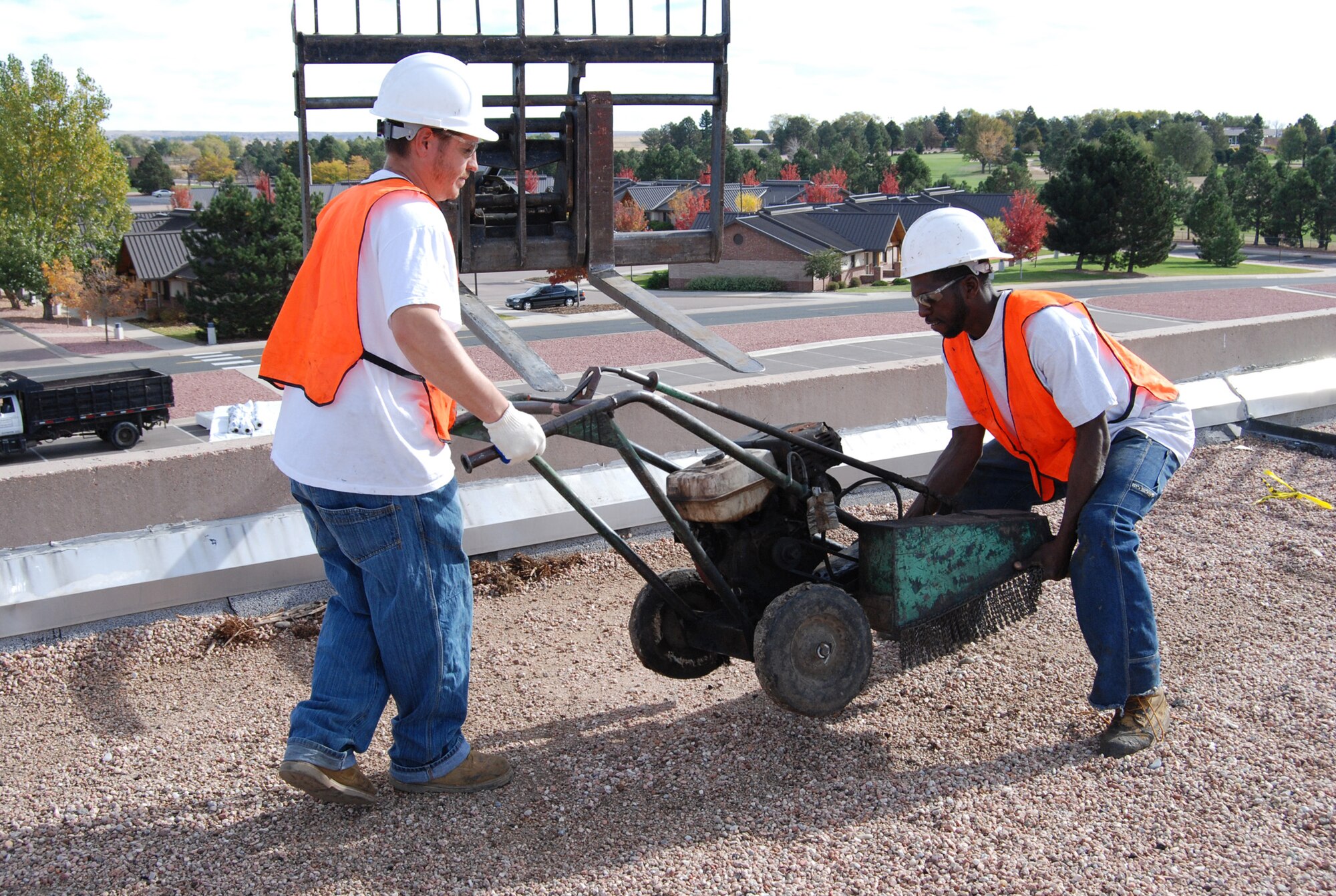 Charles Williams (right) and Dan Esquibea, employees with Weathercraft, unload equipment onto the Building 845 roof. Weathercraft will remove and waterproof the existing roof before the addition of the green roof. (U.S. Air Force photo by Steve Brady)