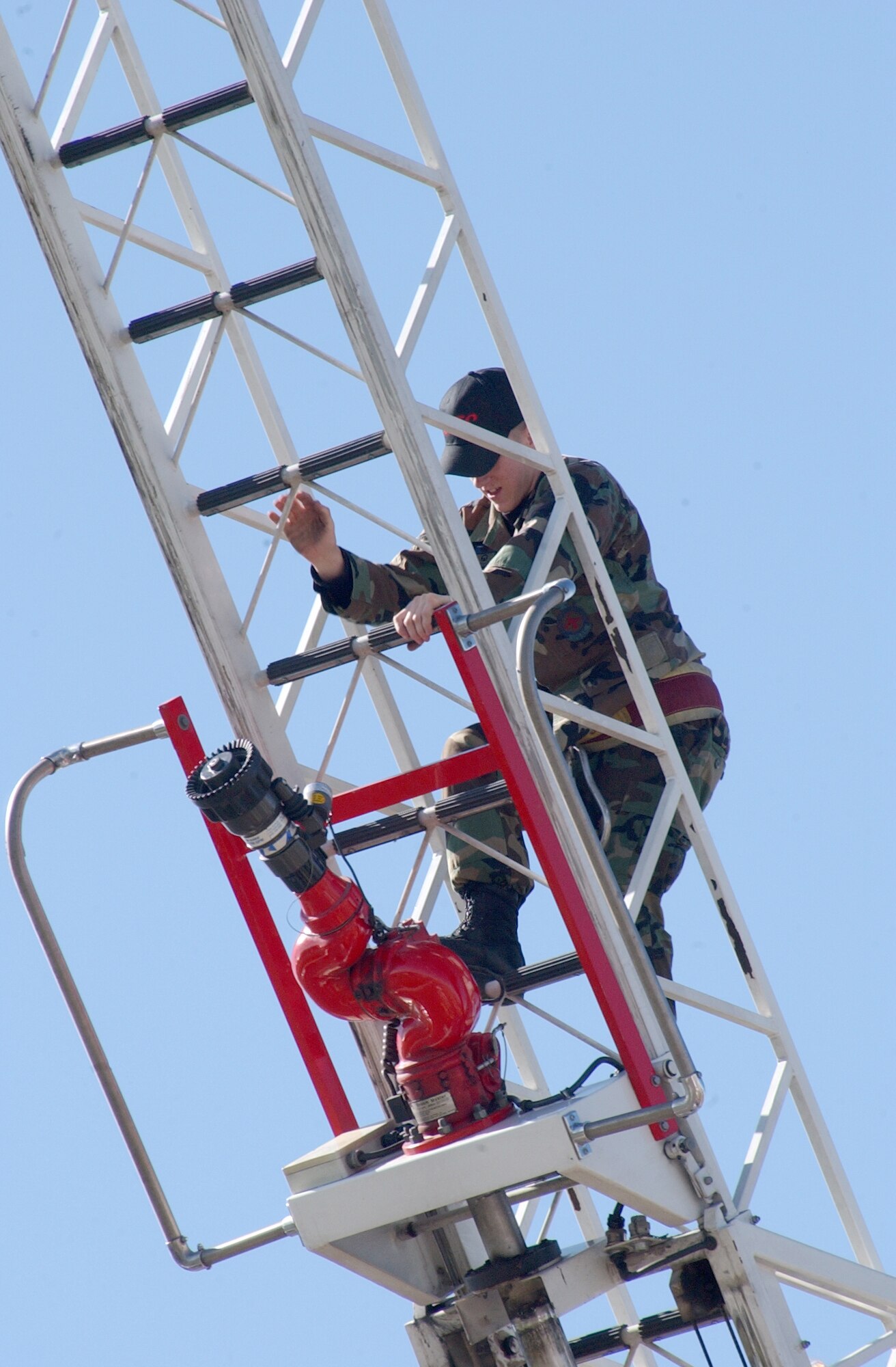 Airman 1st Class Scott Avis, 341st Civil Engineer Squadron firefighter, scales a Great Falls Fire Department fire truck ladder prior to a parade comprised of fire trucks from local and surrounding communities. (U.S. Air Force photo/Airman 1st Class Dillon White)     