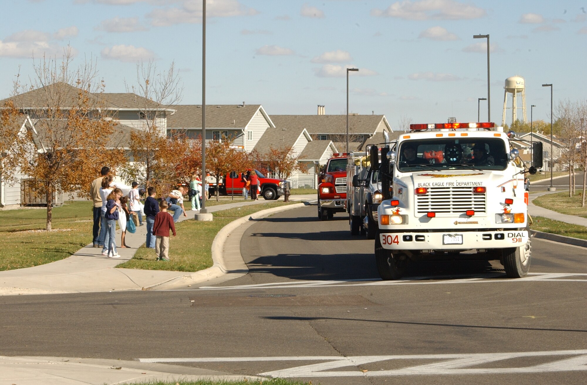 Families line up along a street in Minuteman Village during the fire truck parade through housing Oct. 13. The parade was the finale of Fire Prevention Week, which included visits to the base library and Child Development Center, tours of the fire department and visits to local schools. The Malmstrom fire department worked in conjunction with the Great Falls fire department and fire resuce teams from around the local area. This year's theme was 'Know your escape plan.' (U.S. Air Force photo / Airman 1st Class Dillon White)
