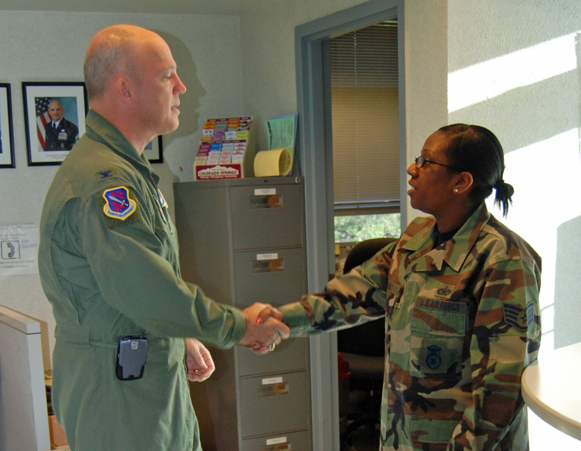 Col. Jay Raymond, 21st Space Wing commander, congratulates Staff Sgt. Sabrina Lukas, 21st Security Forces Squadron, for a job well done. Sergeant Lukas identified and denied access to a man impersonating a general. (U.S Air Force photo by Tech. Sgt. Kimberley Young)