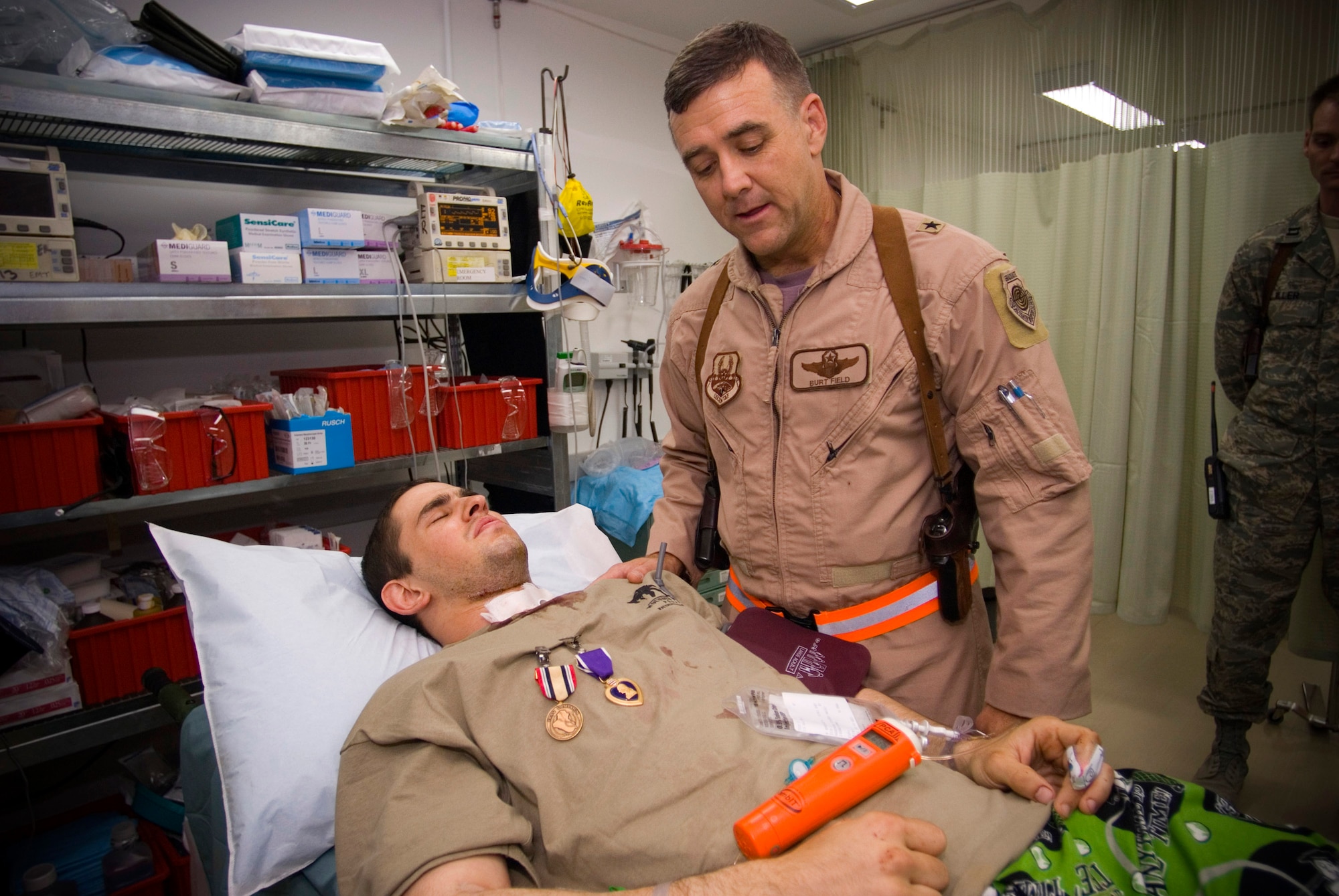 Airman 1st Class Michael Brady receives the Iraq Campaign Medal and the Purple Heart from Brig. Gen. Burton M. Field, commander of the 332nd Air Expeditionary Wing, at the Air Force Theater Hospital at Balad Air Base, Iraq, Oct. 14. Airman Brady earned the medals while augmenting the Army in a non-traditional "in-lieu-of" tasking where he was wounded by sniper fire while on patrol in Ad Diwaniyah, Iraq. Airman Brady is a combat cameraman assigned to the 732nd Air Expeditionary Group. (U.S. Air Force photo/Master Sgt. John Nimmo Sr.)