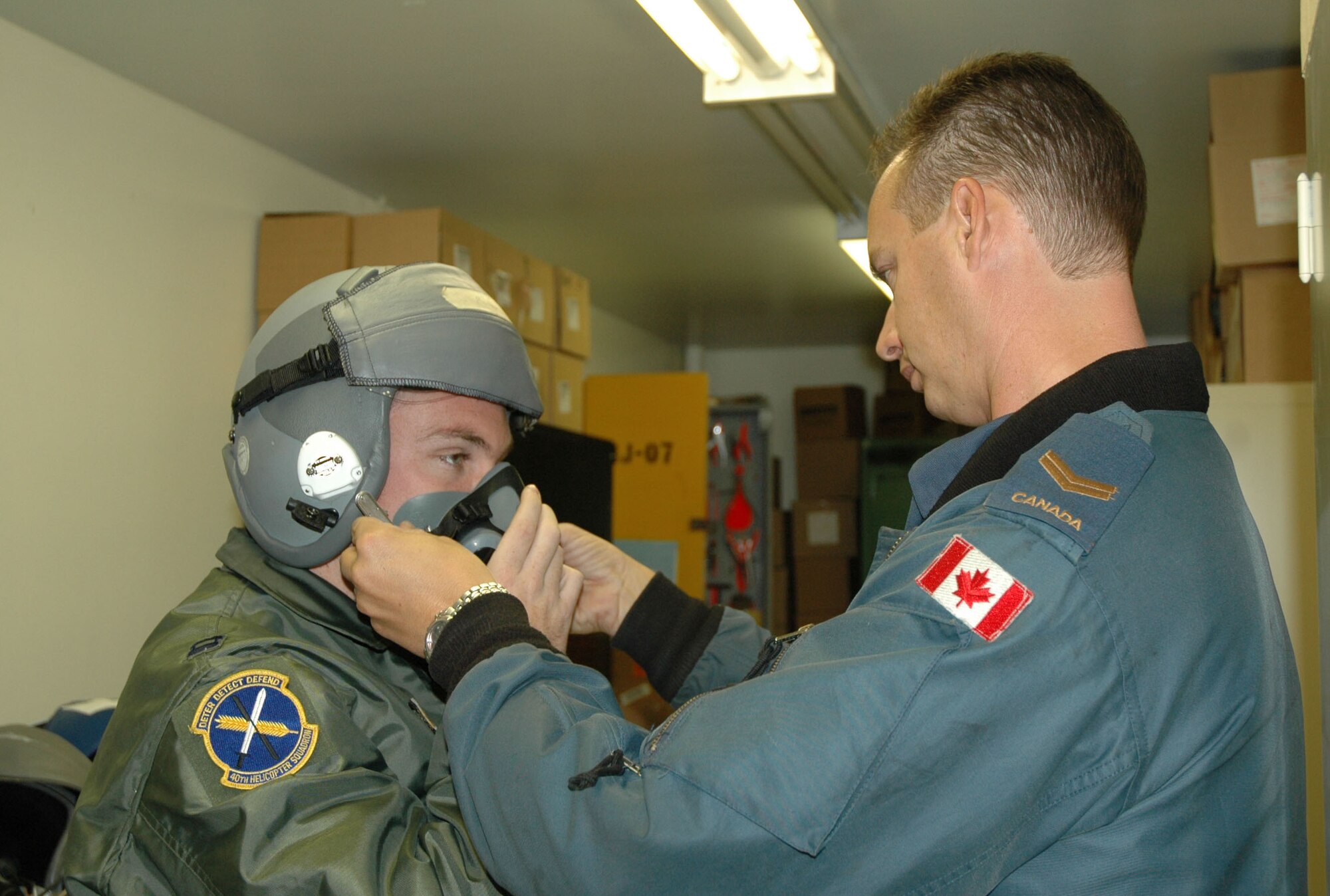 Capt. James McCue, 40th Helicopter Squadron pilot, gets fitted for his helmet and mask by Canadian Forces Cpl. Rob Parker, aviation system technician, Oct. 11 prior to an incentive flight with the Snowbirds in Moose Jaw, Saskatchewan. The Snowbirds wanted to thank Malmstrom for their efforts in May after one of their pilots died during a practice flight on base. (U.S. Air Force photo/Senior Airman Eydie Sakura).