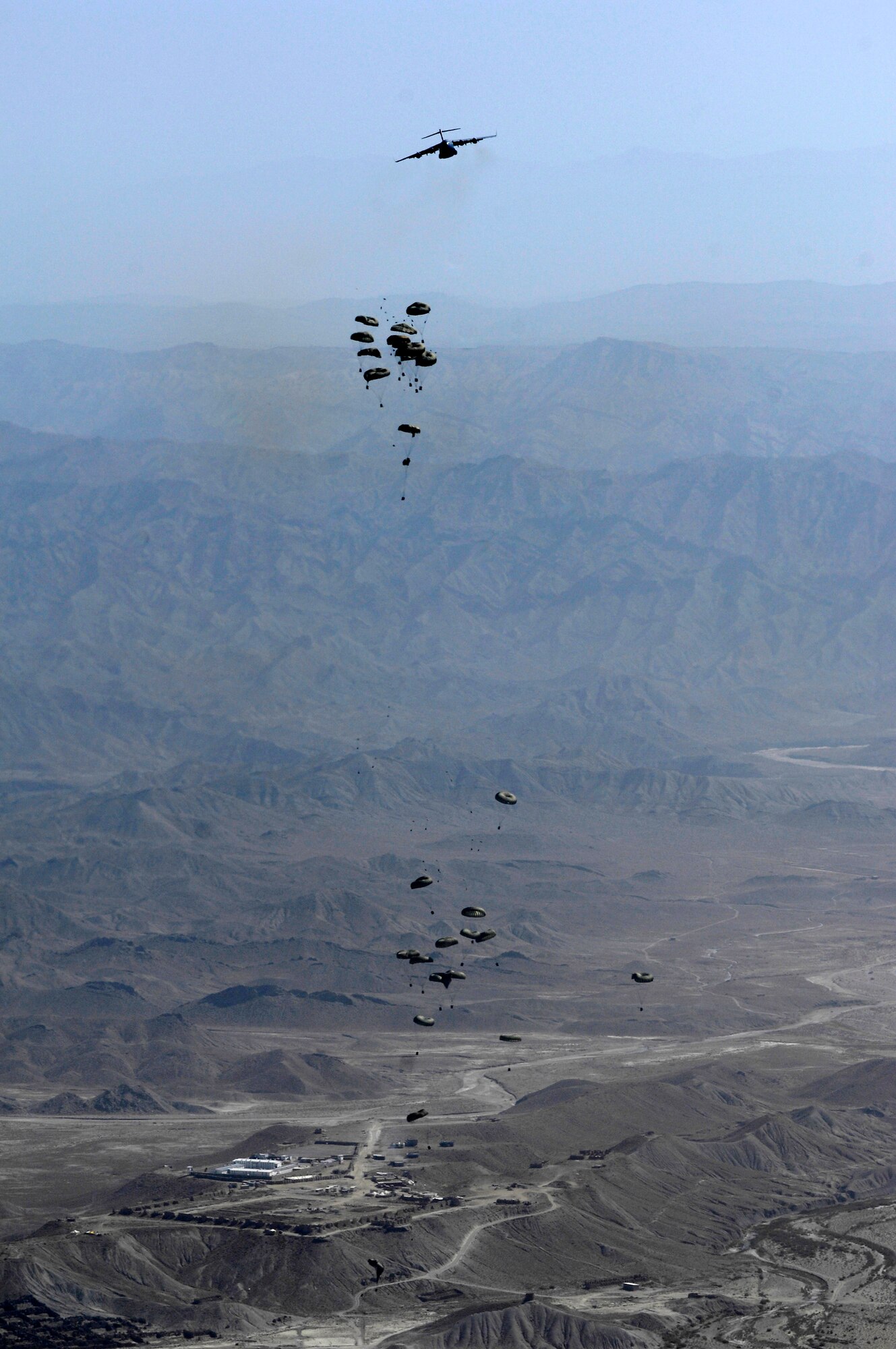As 16 bundles from the lead C-17 Globemaster III drift to the ground, a second C-17 drops more bundles to a drop zone Oct. 11 in Afghanistan. A total of 62 cargo bundles were dropped from two C-17s in two passes. This was the first time a combat cargo drop of this magnitude has taken place from two C-17s in formation over one drop zone. The planes and crews are part of the 817th Expeditionary Airlift Squadron at Manas Air Base, Kyrgyzstan. (U.S. Air Force photo/Staff Sgt. Brian Ferguson)
