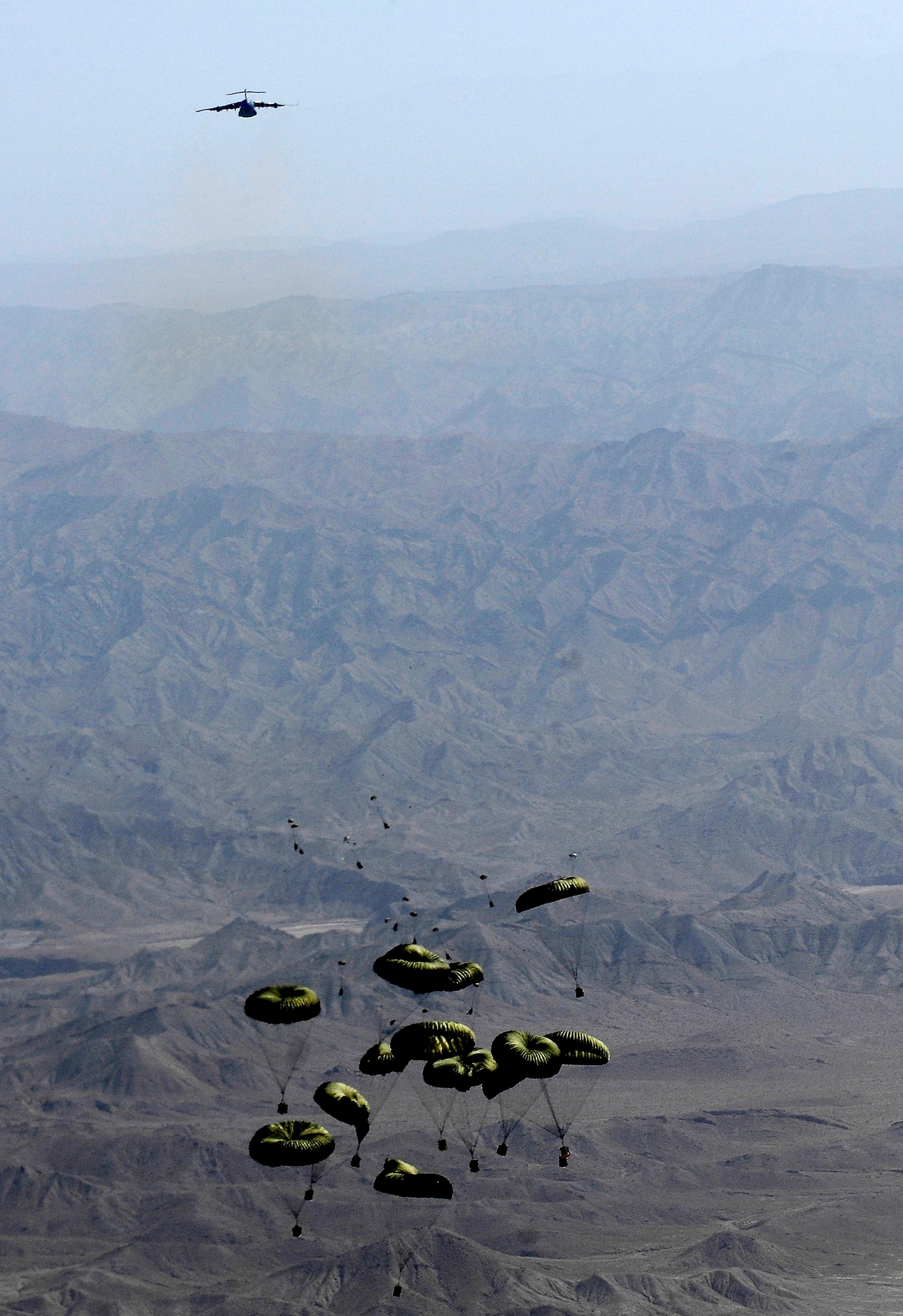 As bundles from the lead C-17 Globemaster III drift to the ground, a second C-17 prepares to drop more bundles to a drop zone Oct. 11 in Afghanistan. A total of 62 cargo bundles were dropped from two C-17s in two passes. This was the first time a combat cargo drop of this magnitude has taken place from two C-17s in formation over one drop zone. The planes and crews are part of the 817th Expeditionary Airlift Squadron at Manas Air Base, Kyrgyzstan. (U.S. Air Force photo/Staff Sgt. Brian Ferguson)

