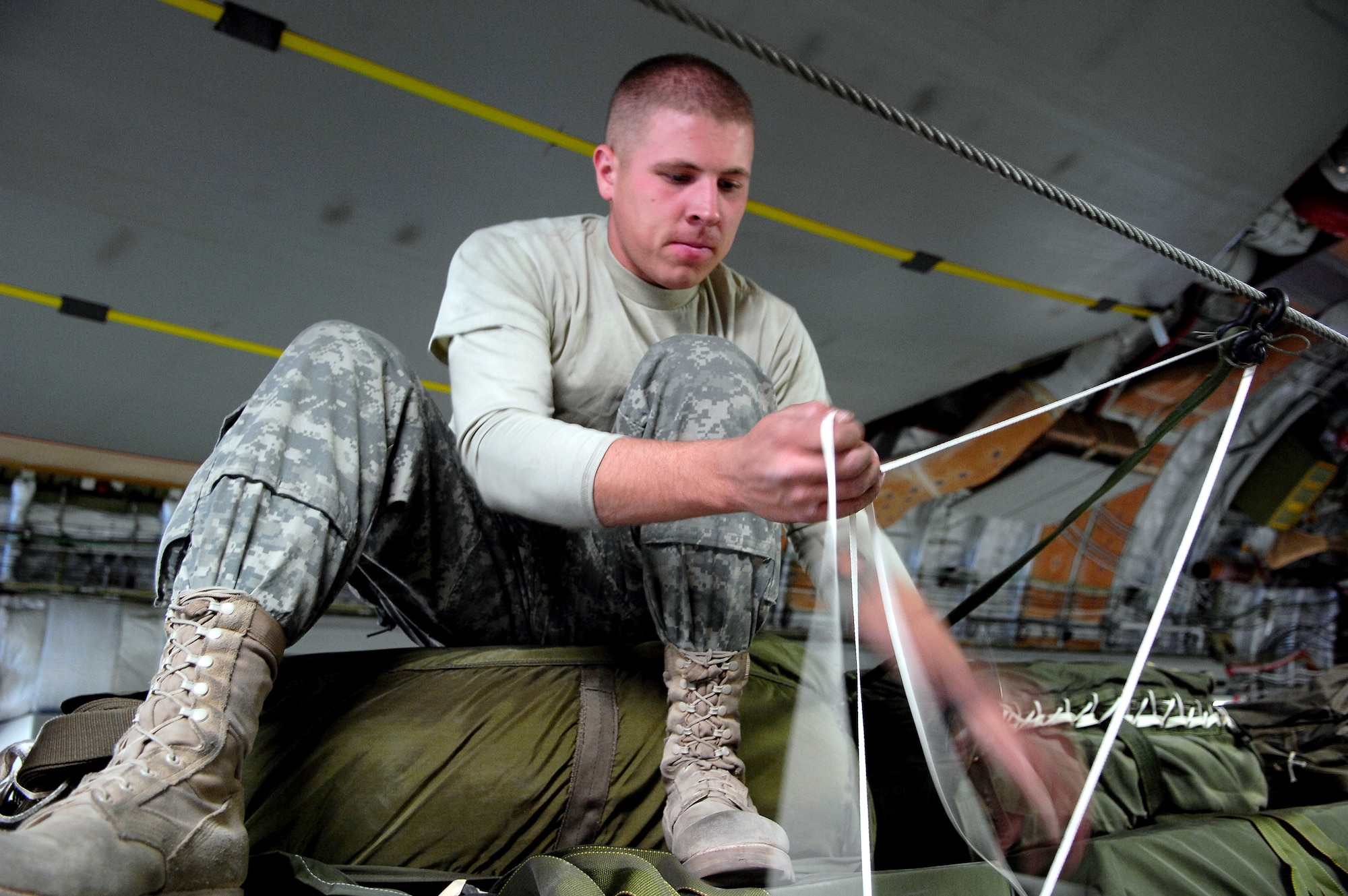 Army Spc. Joshua Black attaches one of 62 parachute ripcords to the static line of a C-17 Globemaster III Oct. 11 at Bagram Air Base, Afghanistan. The 62 cargo bundles were dropped from two C-17s to a drop zone in Afghanistan. This was the first time a combat cargo drop of this magnitude has taken place from two C-17s in formation over one drop zone. Specialist Black is a rigger with the 11th Quartermaster Company, 82nd Airborne. (U.S. Air Force photo/Staff Sgt. Brian Ferguson)
