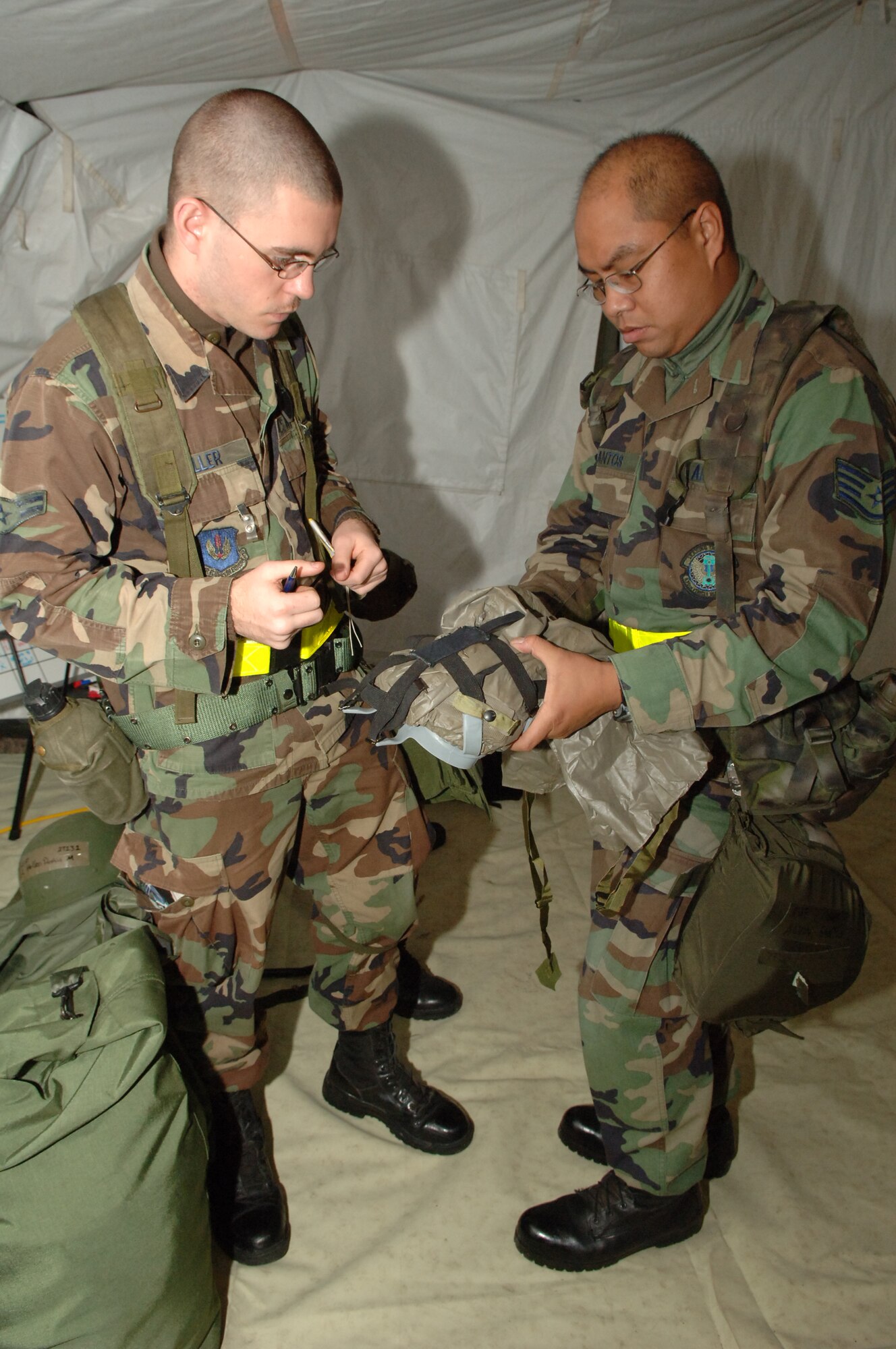 Staff Sgt. Alvin Santos, 435th Vehicle Readiness Squadron vehicle operator (right), shows Airman 1st Class Dustin Holler (left), 435th Vehicle Readiness Squadron vehicle operator, how to properly store his gas mask during the Operational Readiness Exercise at the field training site on Ramstein Air Base, Germany, Oct. 15. The exercise is designed to test the ability of Airmen to survive in austere environments with chemical, biological, radiological, nuclear and explosive hazards.  (U.S. Air Force Photo by Airman 1st Class Kelly LeGuillon) 