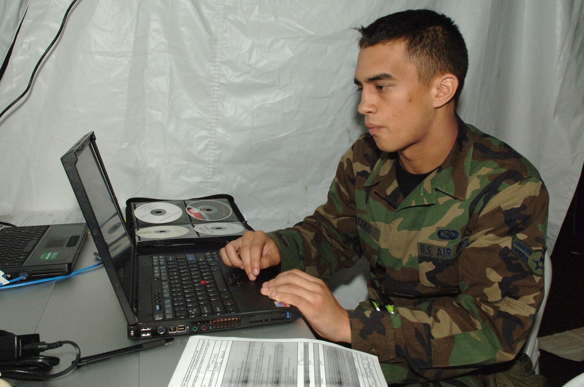 Airman 1st Class Jeffrey Fotakis, 1st Combat Communications Squadron data technician, configures a user laptop so that it can be added to the computer network during the Operational Readiness Exercise at the field training site on Ramstein Air Base, Germany, Oct. 15. The exercise is designed to test the ability of Airmen to survive in austere environments with chemical, biological, radiological, nuclear and explosive hazards.  (U.S. Air Force Photo by Airman 1st Class Kelly LeGuillon) 