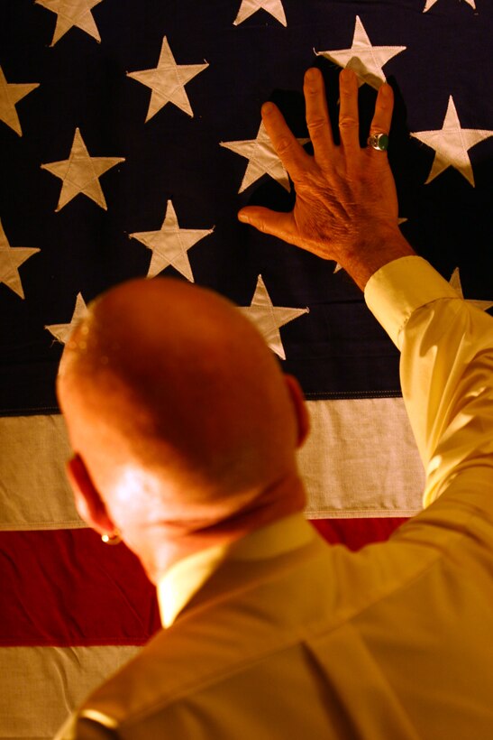 San Diego journalist and former Navy photographer Leo Laurence, J.D., touches an American flag that now is displayed on a wall inside Riley?s Sports and Music Lounge. The flag was presented to Laurence after his Marine friend fell in Iraq.