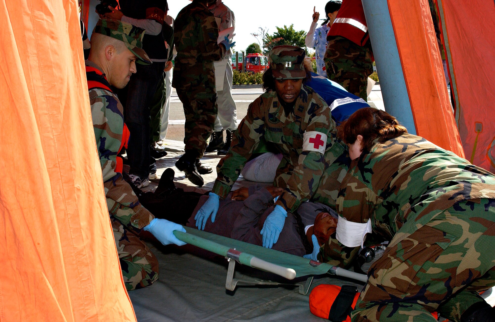 Navy Petty Officer 2nd Class Orlando Garcia (from left), Capt. Mefter Perkins and Capt. Deborah Hoffman prepare a victim for transport as part of the Misawa City Disaster Preparation Exercise at the Misawa Ice Arena Oct. 14 in Japan. This exercise involved members from the U.S. Air Force and Navy, as well as Misawa City first responders. (U.S. Air Force photo/Airman 1st Class Eric Harris)
