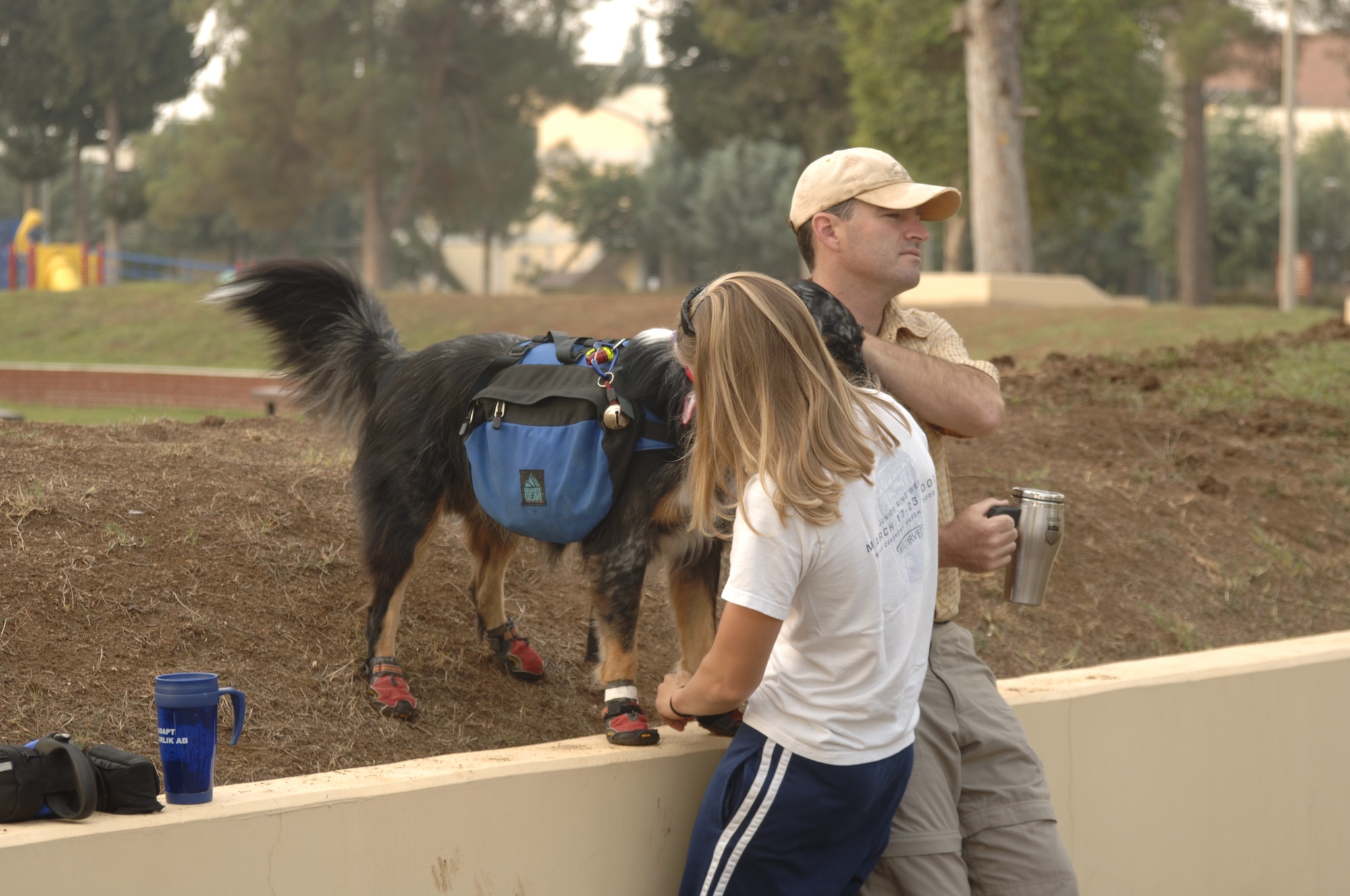Jodi Whitener, 39th Services Squadron Marketing assistant, puts her dog Kipper's boots on to complete the hiking costume while Christopher Whitener, 39th SVS Outdoor Recreation manager, awaits the costume contest winner announcements on Oct. 13. The Whiteners, along with 20 other people and their dogs, came out to Arkadas Park for the second annual Halloween dog costume contest. (U.S. Air Force photo by Senior Airman Tiffany Colburn)
