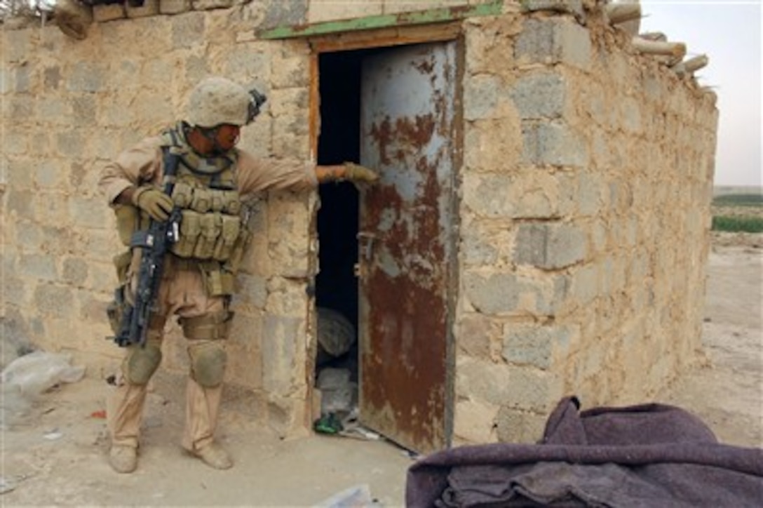 A U.S. Marine attached to 311 Military Transition Team, 3rd Infantry Division, II Marine Expeditionary Force searches outside and inside a house while on a dismounted foot patrol during an operation in Tharthar, Iraq, on Oct. 7, 2007.  
