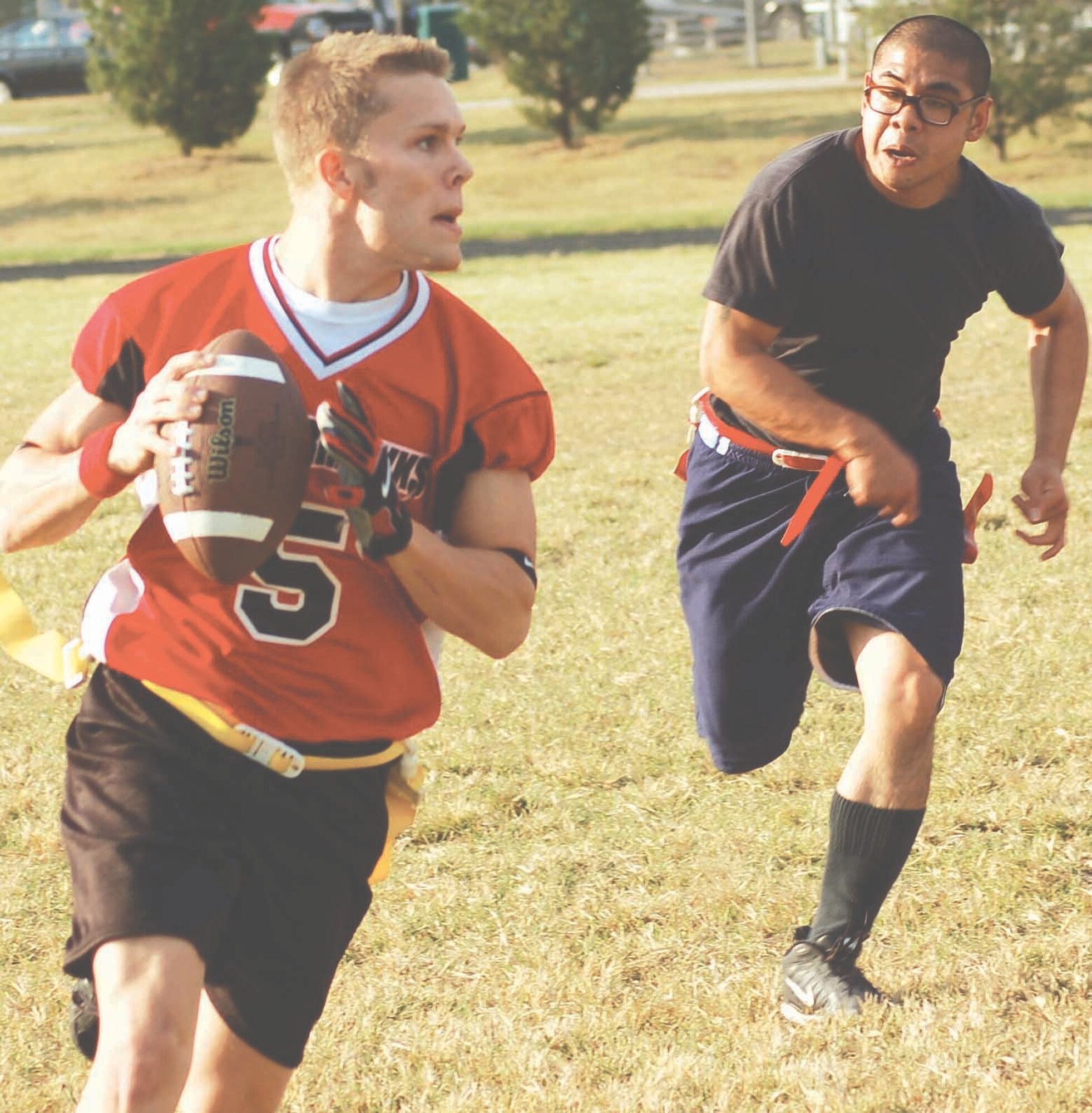 72nd Operational Support Squadron quarterback Justin Hackbarth tries to avoid 964th AACS defender John Aquino during intramural football action on Oct. 12 at the Tinker Sports Complex. 72nd OSS won the game in overtime by yardage gained. (Air Force photo by John E. Banks)