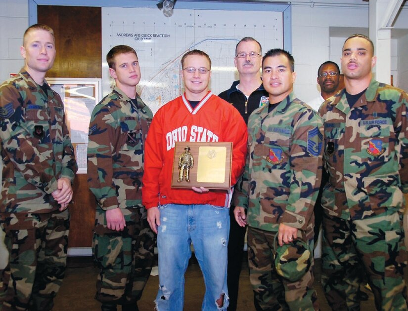 79th Medical Wing team members receive the first place plaque for winning the Annual Fire Fighters Challenge 316th Civil Engineer Squadron Fire Chief Paul Pitrat, rear, and Asst. Fire Chief Christopher Parks, second from right, after the Fire Fighter Challenge Oct. 12. (US Air Force/Bobby Jones)