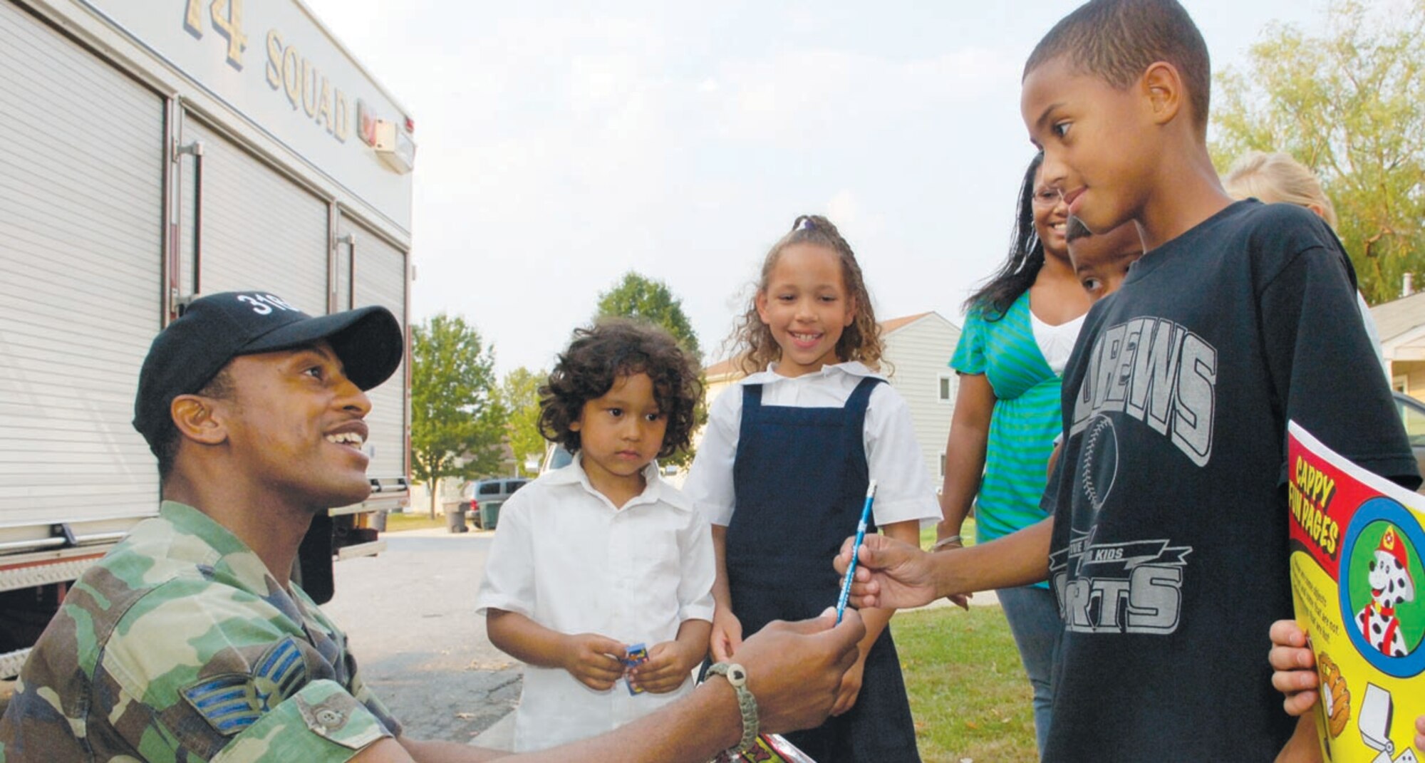 Staff Sgt. Daniel A. Robinson, 316th Civil Engineer Squadron lead fire inspector, gives a pencil to his son, Shawn, 9. Sergeant Robinson also passed out other fire prevention flyers and coloring books, Oct. 11. (US Air Force/A1C Renae Kleckner)