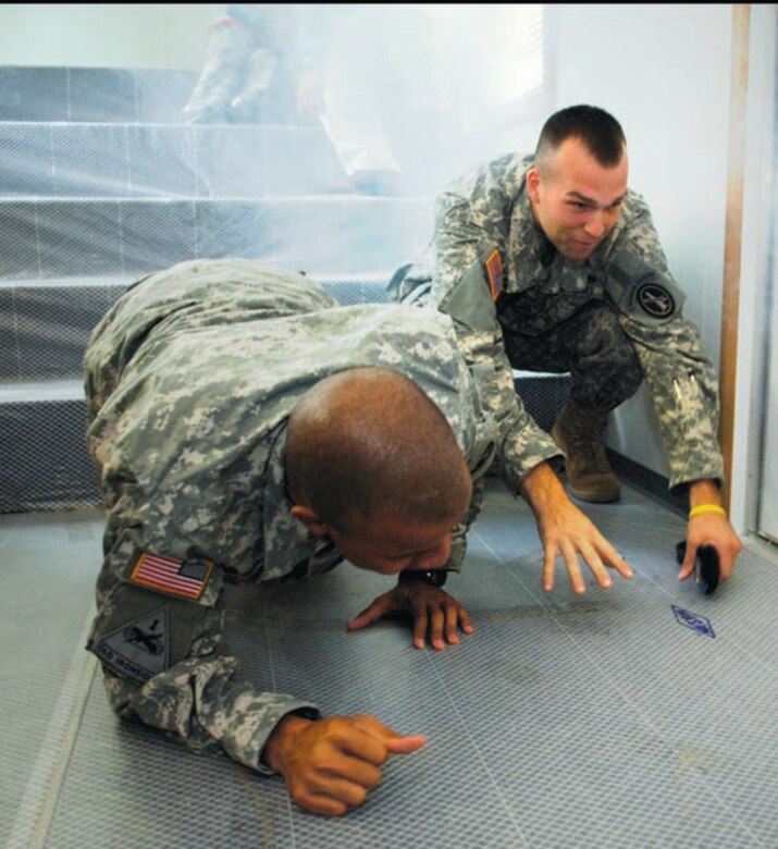 Two Army members crawl on the ground during a simulated fire drill inside a smoke trainer trailer. The drill was to educate children and parents about how to evacuate their home during a fire. (US Air Force/A1C Renae Kleckner)