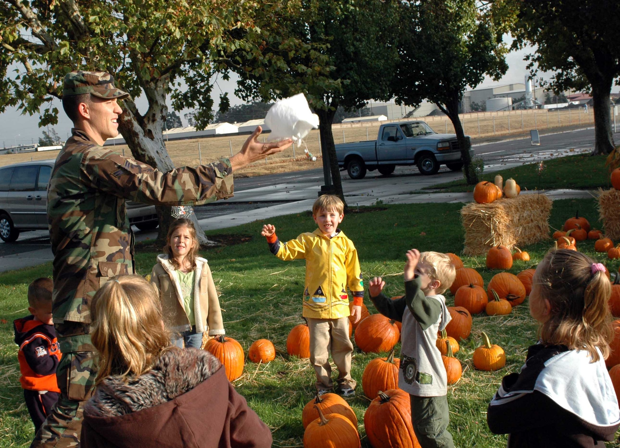 Airman 1st Class Ryan Williams, Operation Candy Drop volunteer, tosses a parachute containing candy to waiting children at Travis Elementary School. Airman Williams is the grandson of 'The Candy Bomber,' Col. Gail Halvorsen, (retired), a Berlin Airlift pilot who delivered candy to children via parachute at the end of World War II. (U.S. Air Force photo/Staff Sgt. Matthew McGovern)