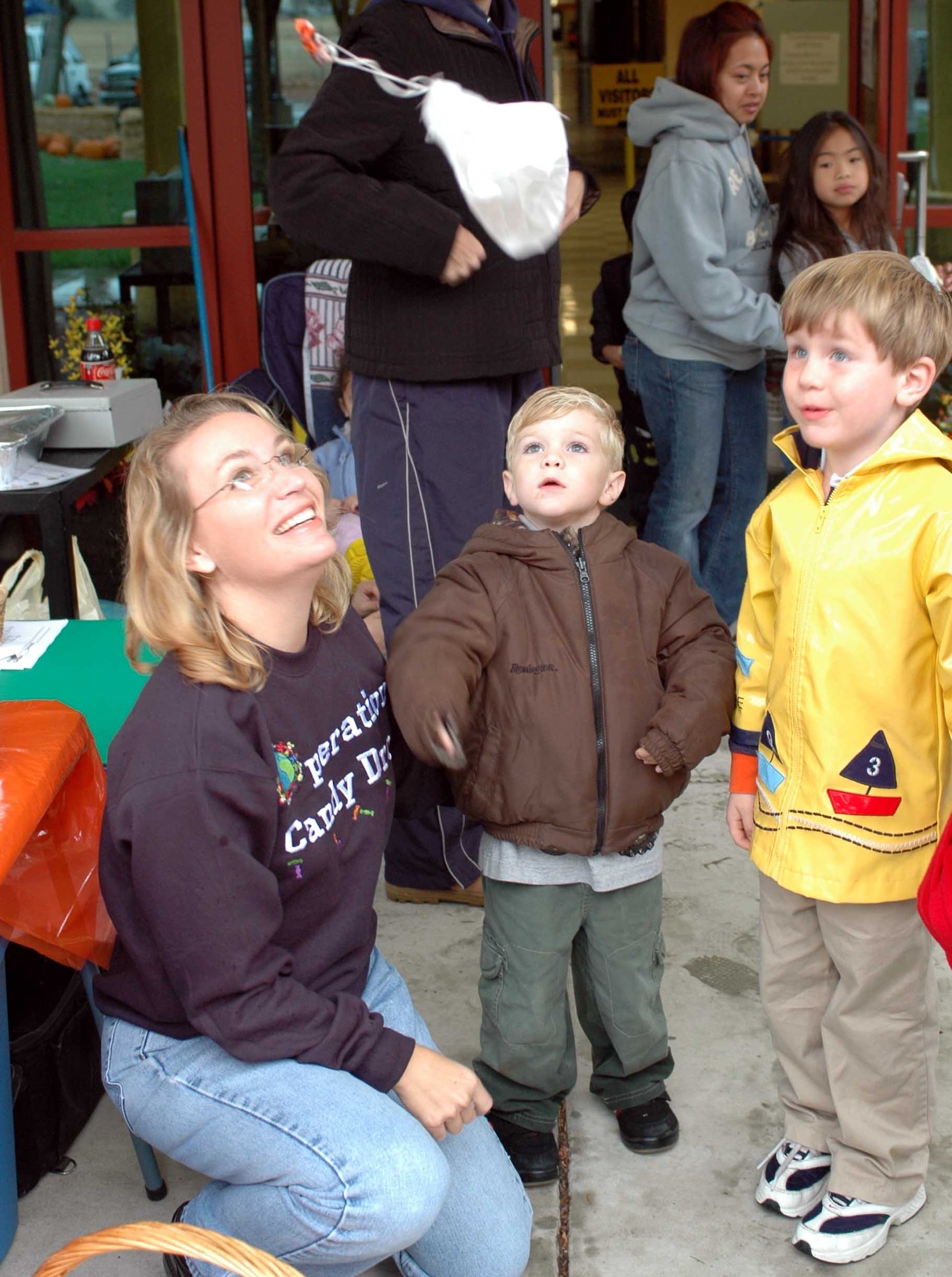 Lori Welch, (left), watches as her son Justin Welch, (middle), and Skylar Farrow, son of Lt. Col. David Farrow, 570th Global Mobility Squadron commander, tosses a parachute containing candy at Travis Elementary School. Operation Candy Drop, a drive to collect and deliver Halloween candy to Iraqi children, will happen Nov. 1 and 2. (U.S. Air Force photo/Staff Sgt. Matthew McGovern) 