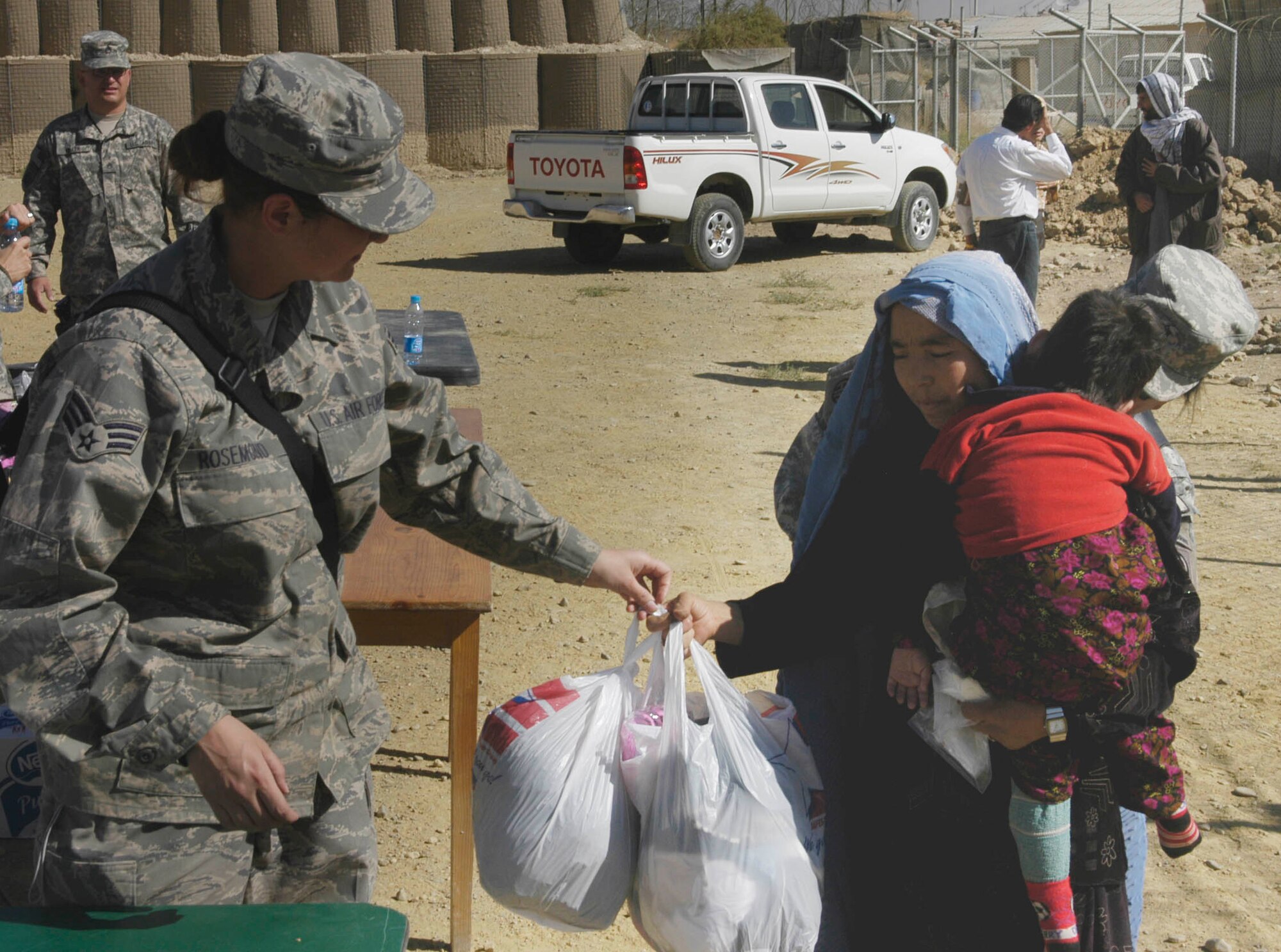 BAGRAM AIRFIELD, Afghanistan -- Air Force Senior Airman Elisa Rosemond pass out bags of clothes to an Afghan mother and her child during an Operation Care visit to the Korean Hospital here Oct. 17.  Operation Care is an all-volunteer effort that provides clothes, school and hygiene supplies, toys and candy to Afghan villagers.  (U.S. Air Force Photo by Capt. Michael Meridith)                
