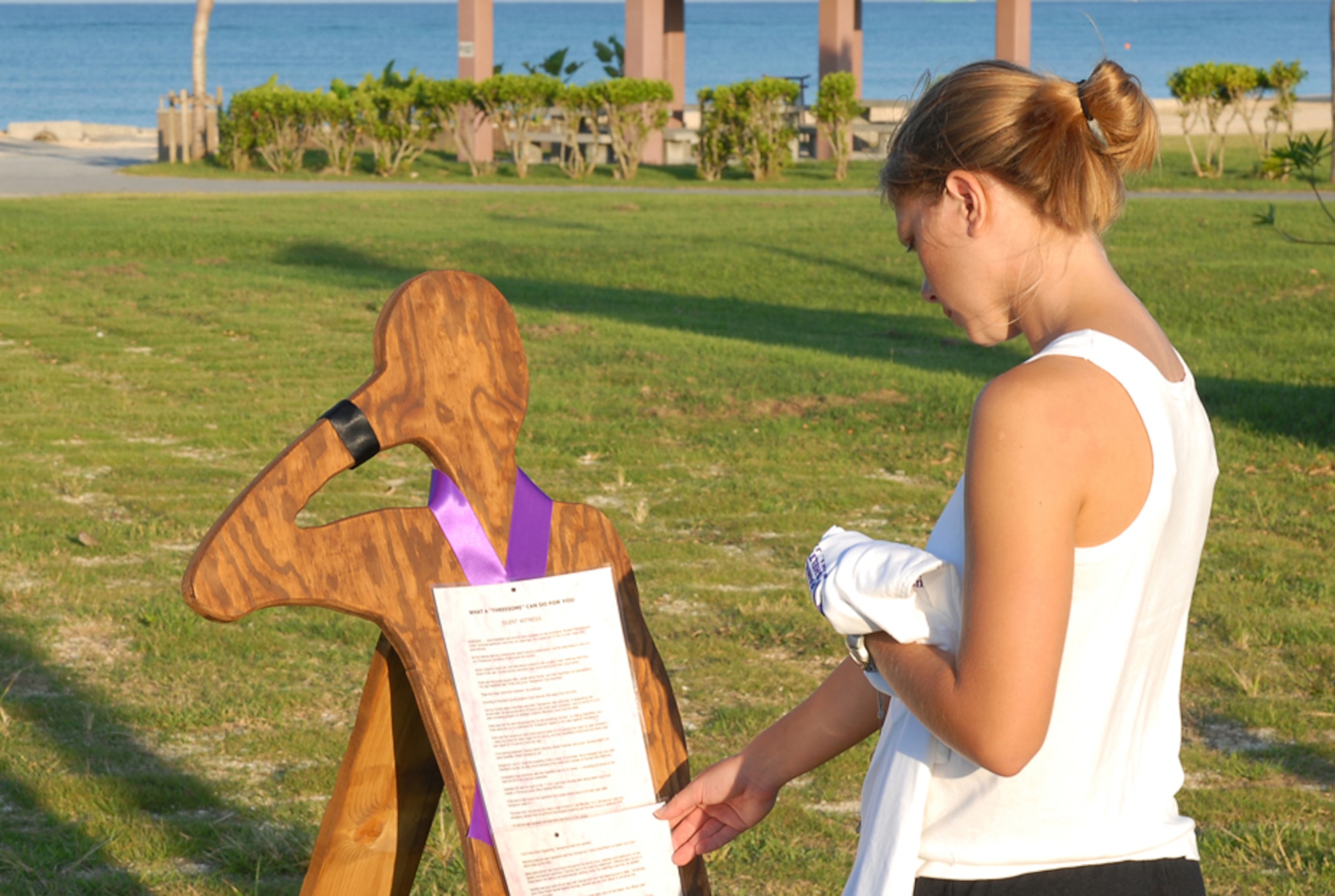 Senior Airman Sheri Mason, 18th Civil Engineer Squadron, reads about the lives of first-hand victims of domestic violence during the 4th Annual Domestic Violence Awareness Run/Walk held on Torri Station, Japan, Oct. 13, 2007. The first-hand accounts were attached to wooden figures to remind participants that human lives were lost in a lot of the cases. Locals, service members of the United States military forces, and Girl Scout troops came from all over the island to participate in the 5K run and walk meant to raise awareness and stop domestic violence in the military community.  (U.S. Air Force/Airman 1st Class Kelly Timney)
