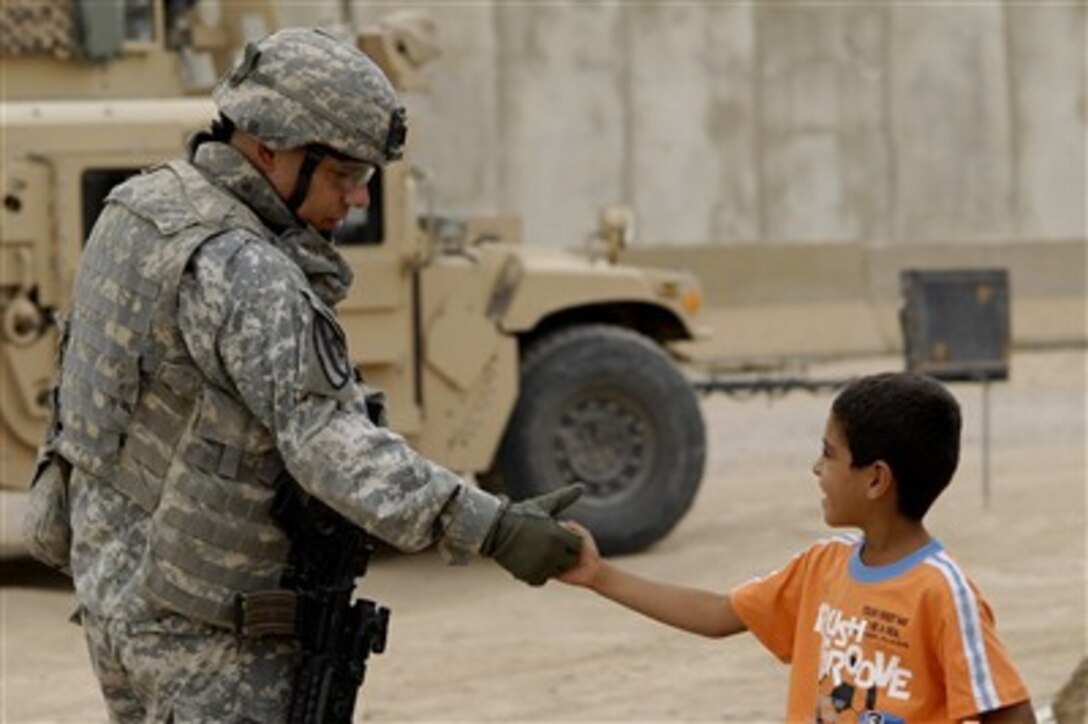 U.S. Army Maj. Robert Rodriguez shakes hands with a local child during a visit to the market in Taji, Iraq, on Oct. 11, 2007.  Rodriguez is the executive officer of 2nd Battalion, 8th Cavalry Regiment, 1st Brigade, 1st Cavalry Division.  