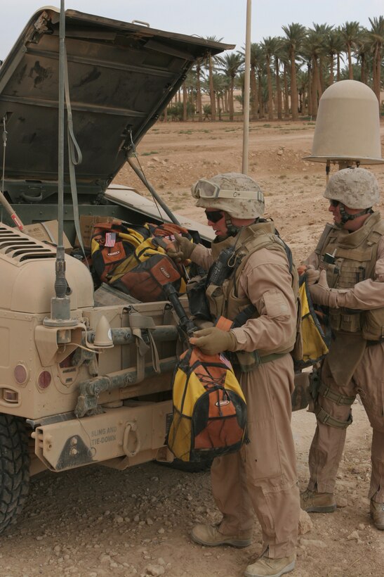 HAWRAN, Iraq - Sgt. Christopher Pickett, left, and Maj. John Bancroft unload backpacks from the back of a Humvee to give to the school in Hawran, Oct. 19. The Marines of Alpha Company, Marine Wing Security Battalion 372 delivered paper, backpacks, and glue to the school. Picket is a squad leader with 2nd Platoon, Alpha Co., and Bancroft is the company commander.
