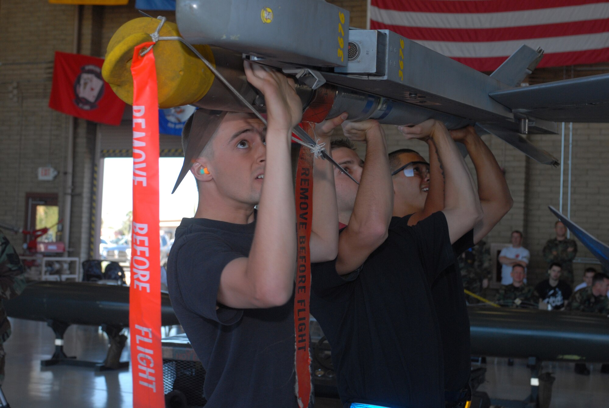 Airman Zebulon Pritchard, Staff Sgt. Josh Fiasco and Airman 1st Class Treston Keaneao, 56th Aircraft Maintenance Squadron, load a missile onto the wing of an F-16 during the load crew of the quarter competition Oct. 11. The winners of the  competition will be announced at 2 p.m. today in Hangar 45. (photo by Airman 1st Class David Bulkley)