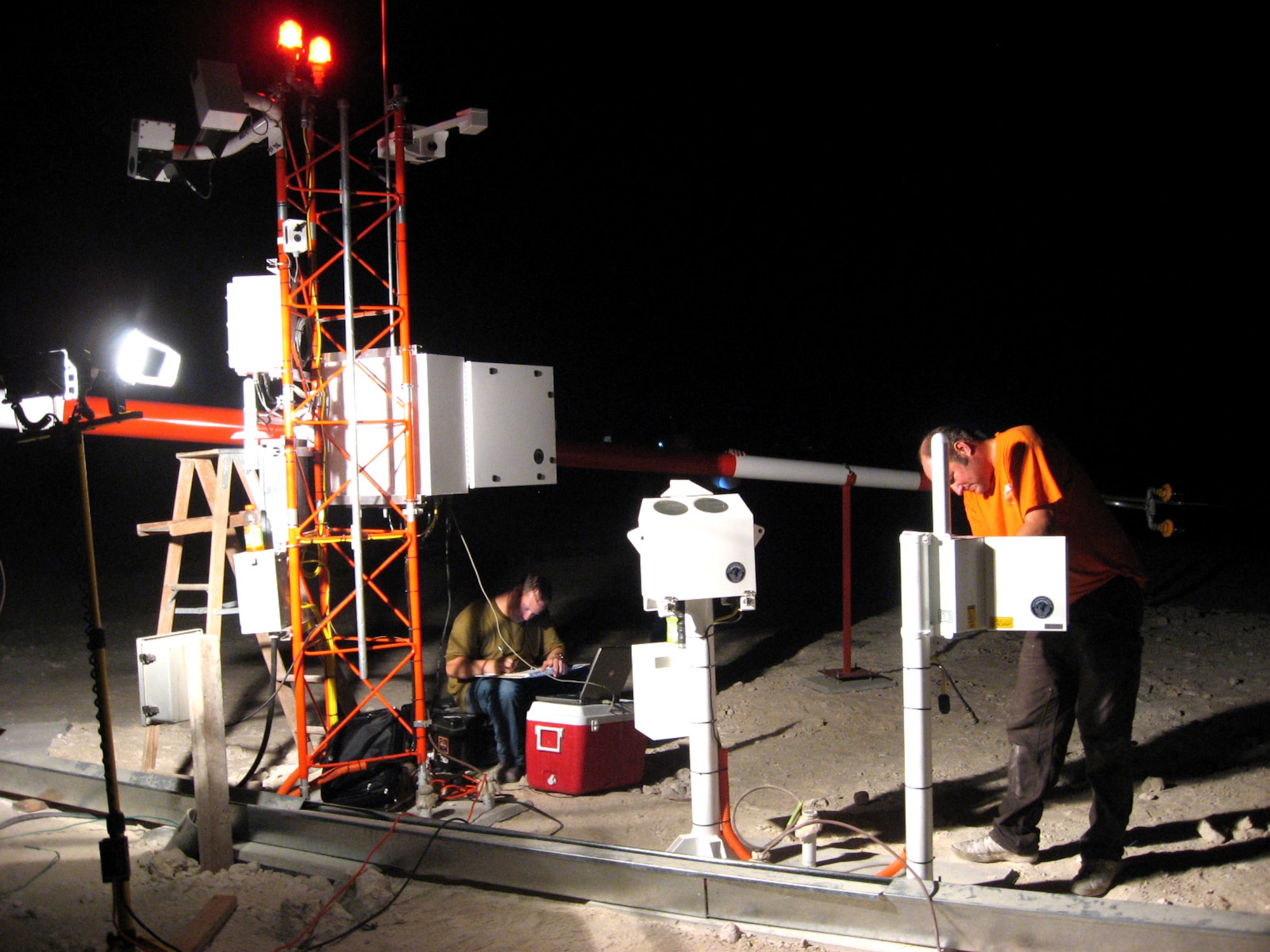 Steve Clark (left) and Dan Smith of Coastal Environmental, Inc. perform site acceptance and testing measures on portions of the FMQ-19 weather sensing system in Southwest Asia. This system was the last of 110 to be installed under a five-year, $70 million effort. System installation at the Southwest Asia location was done mainly at night, as day-time temperatures often exceeded 100 degrees. (Courtesy photo)