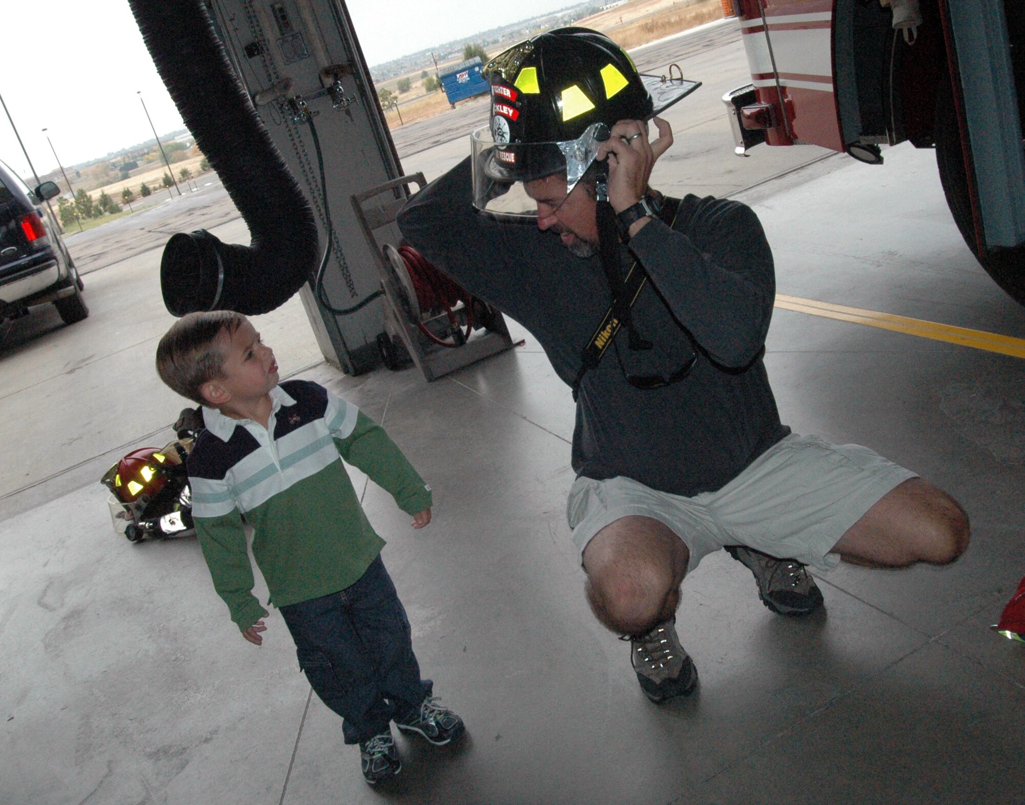 BUCKLEY AIR FORCE BASE, Colo. -- Dave McGowan, a military spouse, models a fireman's helmet for his son Callahan during the Buckley Fire Department's open house Oct. 13. The fire department hosted an open house and conducted a fire truck parade through base housing that day to celebrate the ending of fire prevention week. (U.S. Air Force photo by Senior Airman Jacque Lickteig)