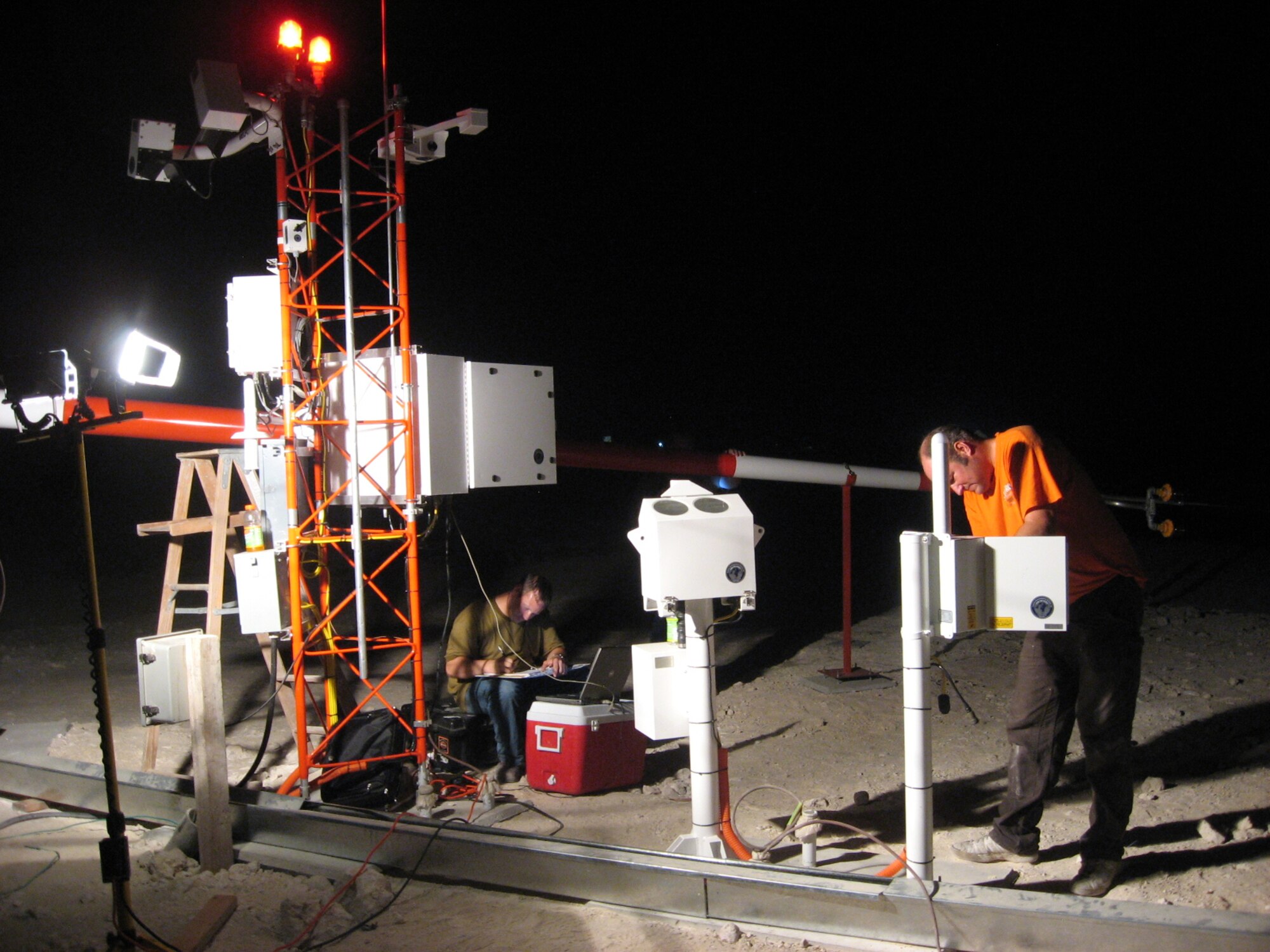 From left, Steve Clark and Dan Smith of Coastal Environmental Inc. perform site acceptance and testing measures on portions of the FMQ-19 weather sensing system at the 379th Air Expeditionary Wing in Southwest Asia., earlier this month, the last of 110 to be installed under a five-year, $70 million effort. System installation was accomplished mainly at night, as day-time temperatures often exceeded 100 degrees. (Courtesy photo)
