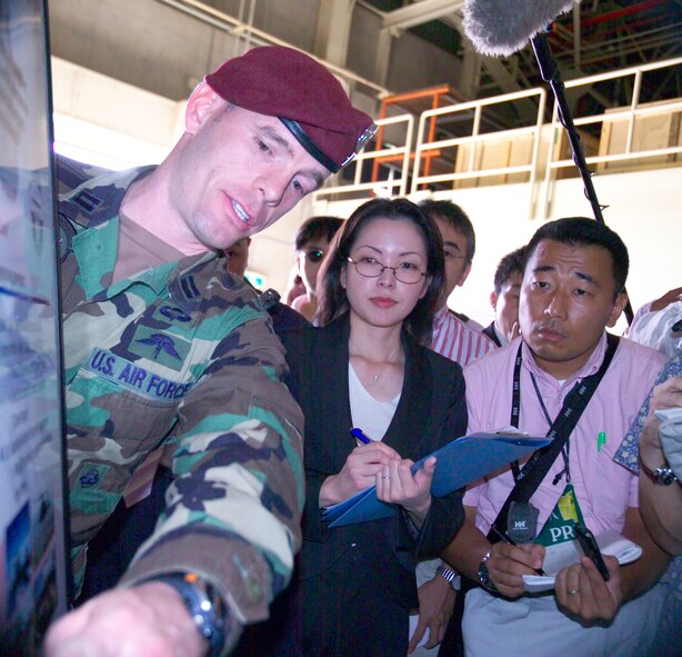 A member of the 31st Rescue Squadron explains to members of the Japanese media capabilities of pararescuemen before a proficiency paradrop on Kadena’s airfield Oct. 19. More than 20 members of the media attended the briefing about the airborne operation and observed the drop.  (courtesy photo/Scott Hallford)