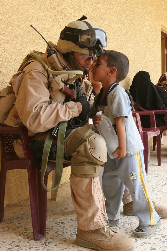Lt. Hammed Najam, an Iraqi soldier with 2nd Battalion, 3rd Brigade, 1st Iraqi Army Division, receives and friendly kiss from a small child after Najam gave him an ice cold bottle of water during a combined medical engagement here Oct. 20.  Marines from 1st Bn., 1st Marine Regiment, Regimental Combat Team 6, also helped the Iraqi army during the CME, which provided Iraqis from the local town of Kahalid a chance to receive free examinations, medical care and prescriptions in a safe and secure environment.