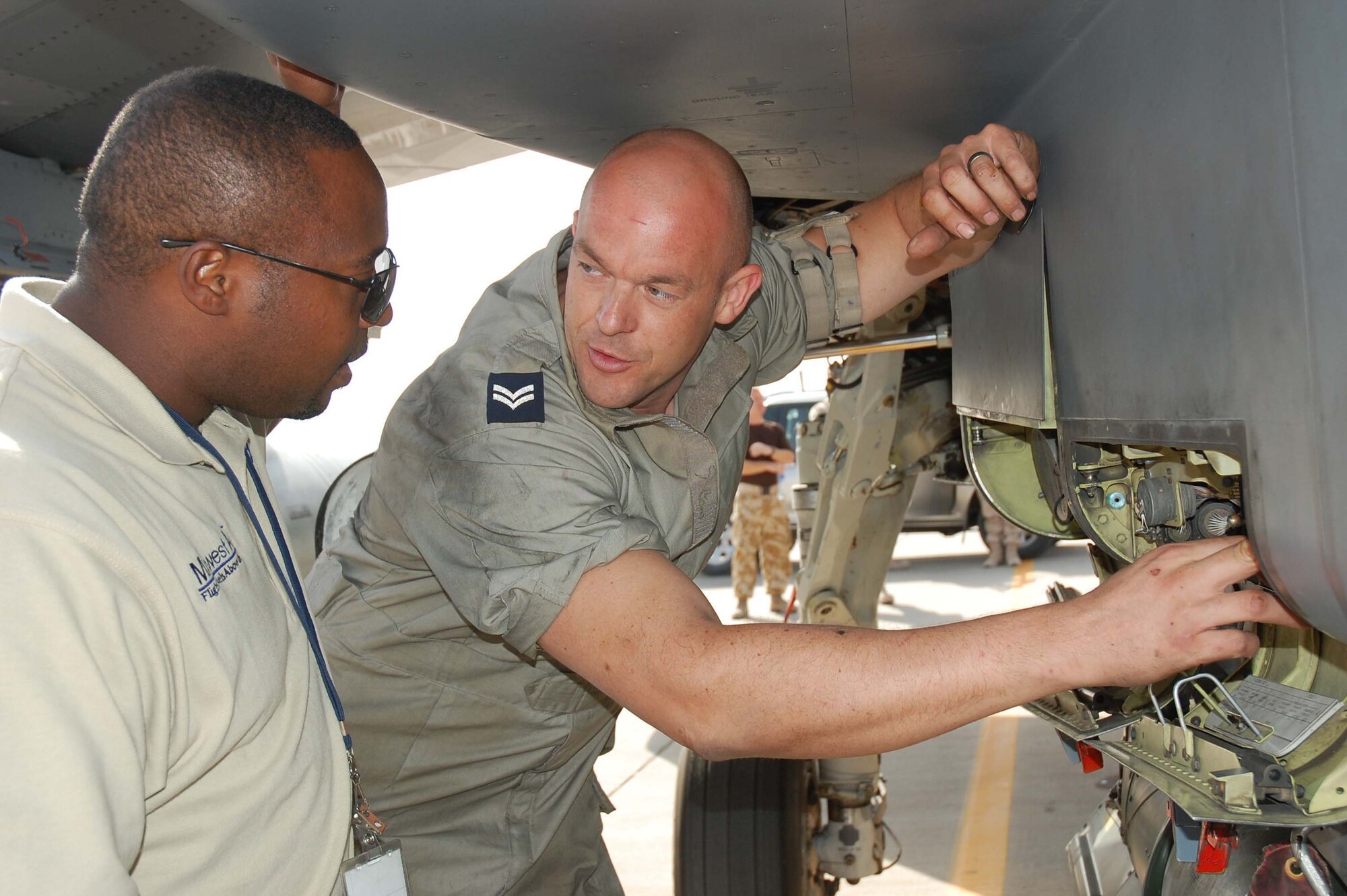 SOUTHWEST ASIA -- Cpl. Paul Stone, Royal Air Force engineer, and Mr. Michael Edwards, 386th Expeditionary Maintenance Group transient alert contractor, conduct a pre-flight inspection on the refuel panel of a Tornado Royal Air Force fighter jet here Oct. 19.  (U.S. Air Force photo by Staff Sgt. Tia Schroeder)
