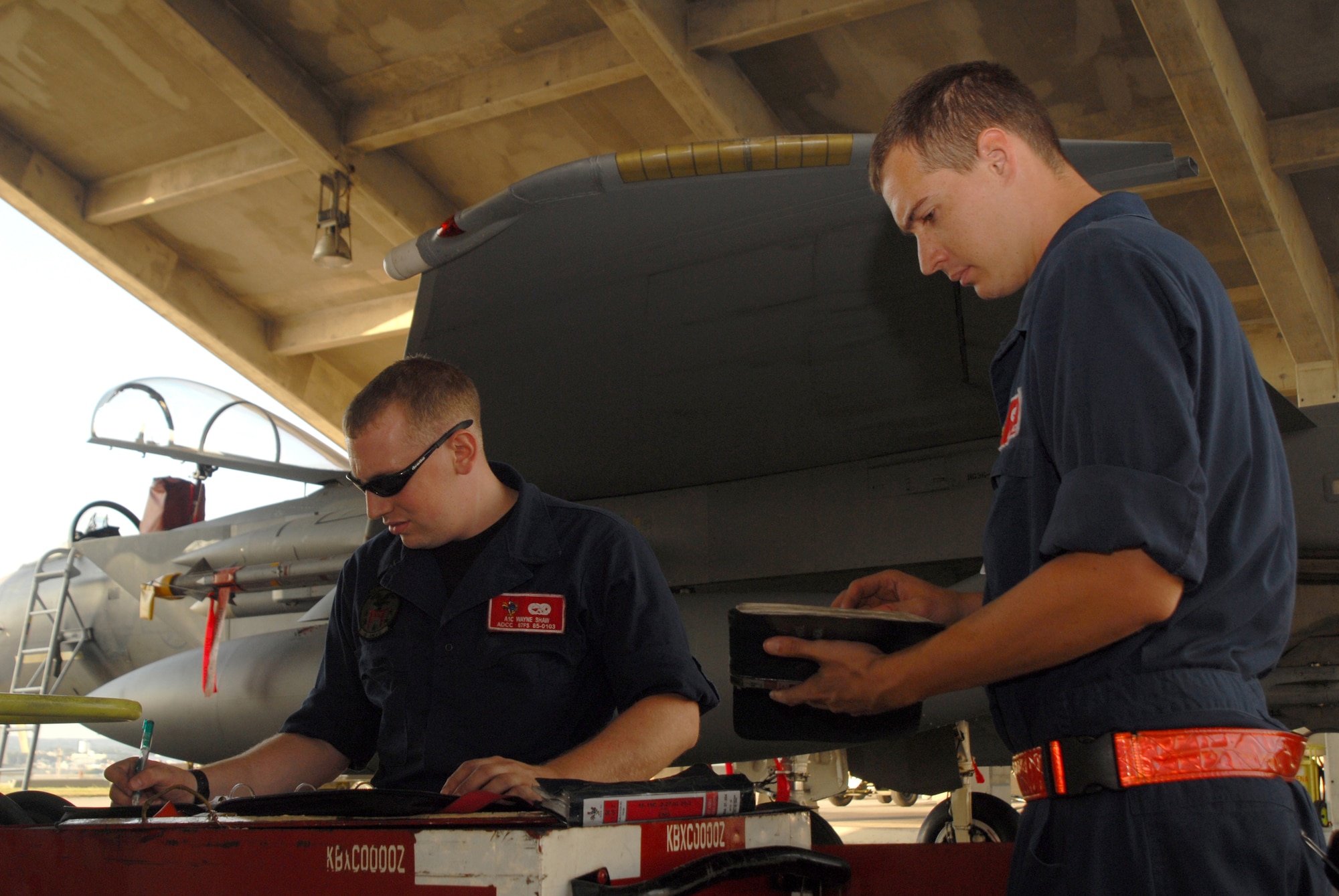 Airman 1st Class Wayne Shaw documents the work performed on an F-15C Eagle while Airman 1st Class Vincent Calace reviews a technical order for reference during Local Operational Readiness Exercise Beverly High 08-1 Oct. 22.  Both Airmen are assigned to the 18th Aircraft Maintenance Squadron, 67th Aircraft Maintenance Unit. (U.S. Air Force photo/Staff Sgt. Chrissy FitzGerald) 