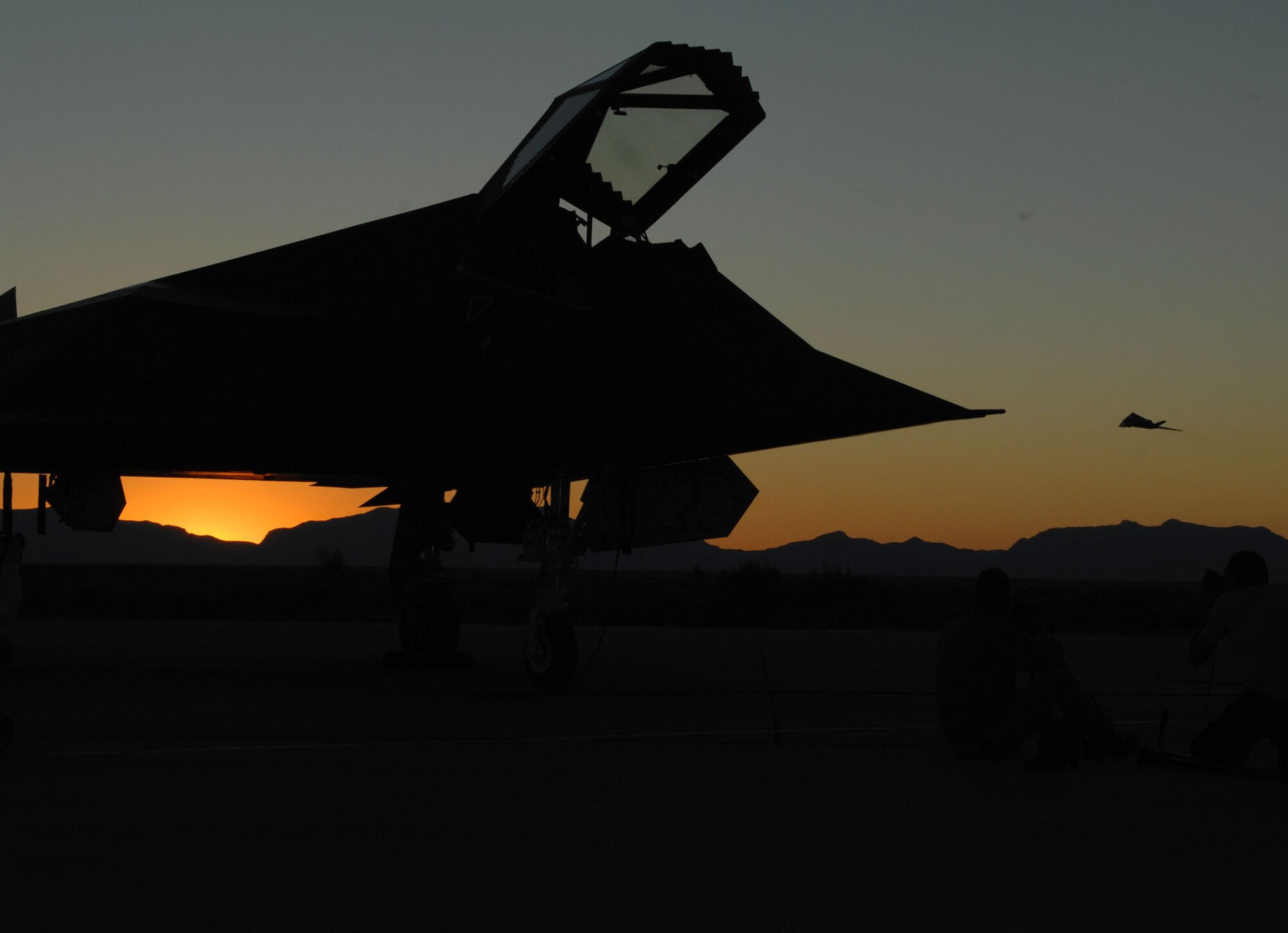 An F-117A Nighthawk sits on the Holloman flightline as another takes off into the sunset. (U.S. Air Force photo/Airman 1st Class Jamal Sutter)