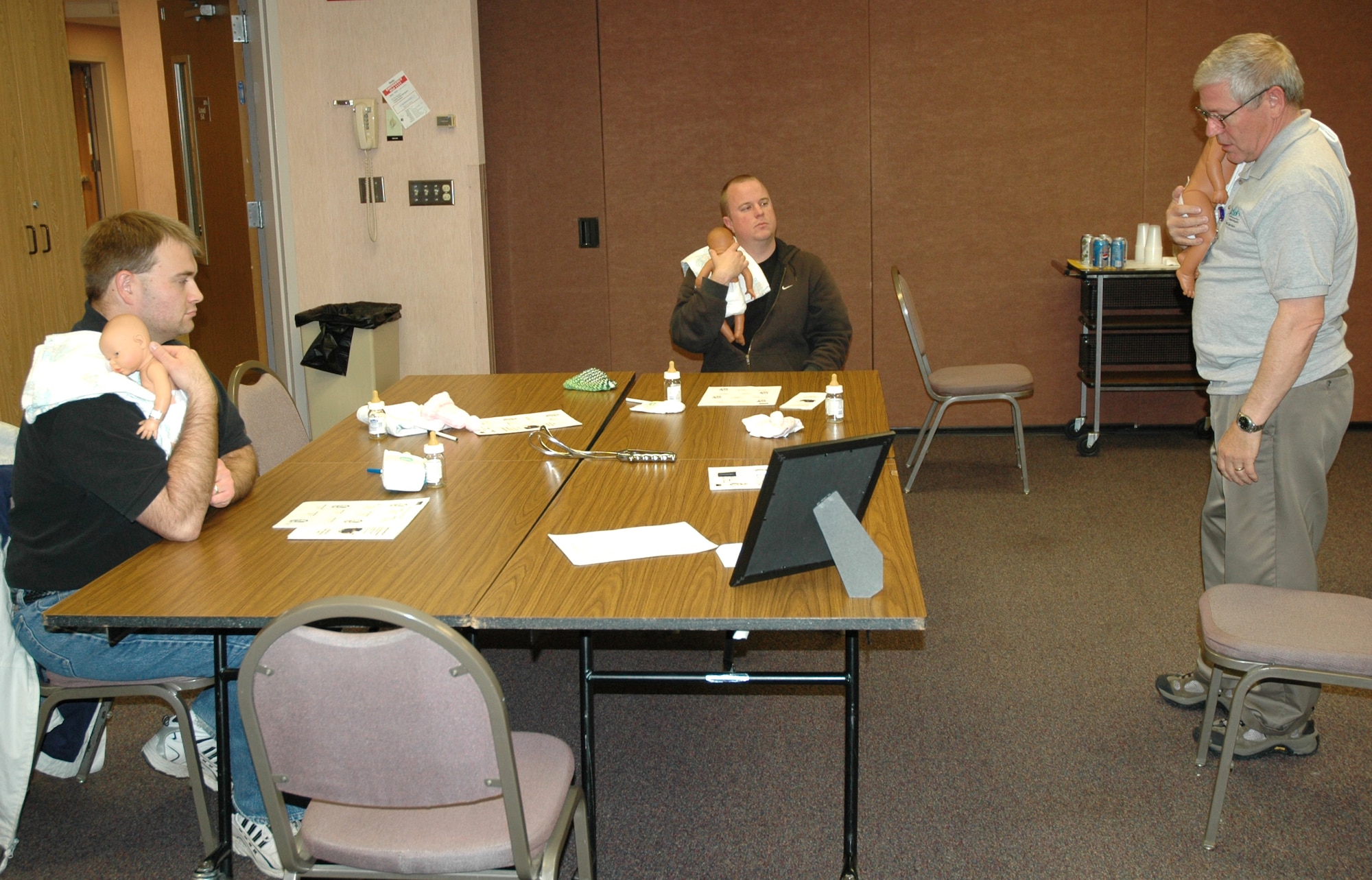 Jason Fisher and Logan Pfeifer listen to Joseph Furr as he demonstrates how to hold a baby during a new father class held at Benefis Health Care 7 p.m. to 9 p.m. Oct. 18. Mr. Furr is a retired U.S. Air Force lieutenant colonel and volunteers his time to teach the class to new fathers. (U.S. Air Force photo/Airman 1st Class Dillon White)