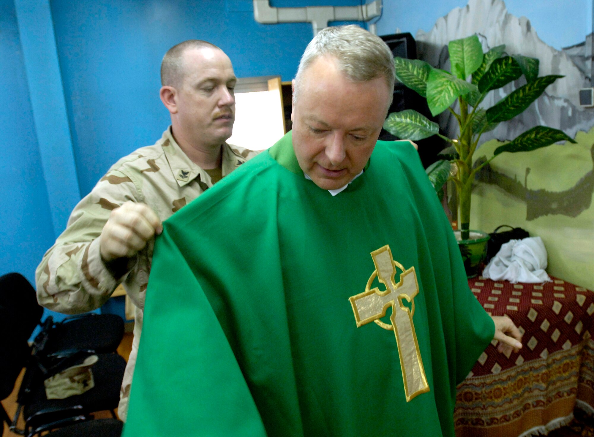 Navy Petty Officer 2nd Class Fred Hays assists Chaplain (Lt. Col.) Michael Weber into his vestments before the Catholic daily mass July 23 at Camp Eggers in Kabul, Afghanistan. Air Force chaplain recruiters brought in 11 active-duty and six Reserve Catholic priests in fiscal 2007. (U.S. Air Force photo/Master Sgt. Jim Varhegyi) 
