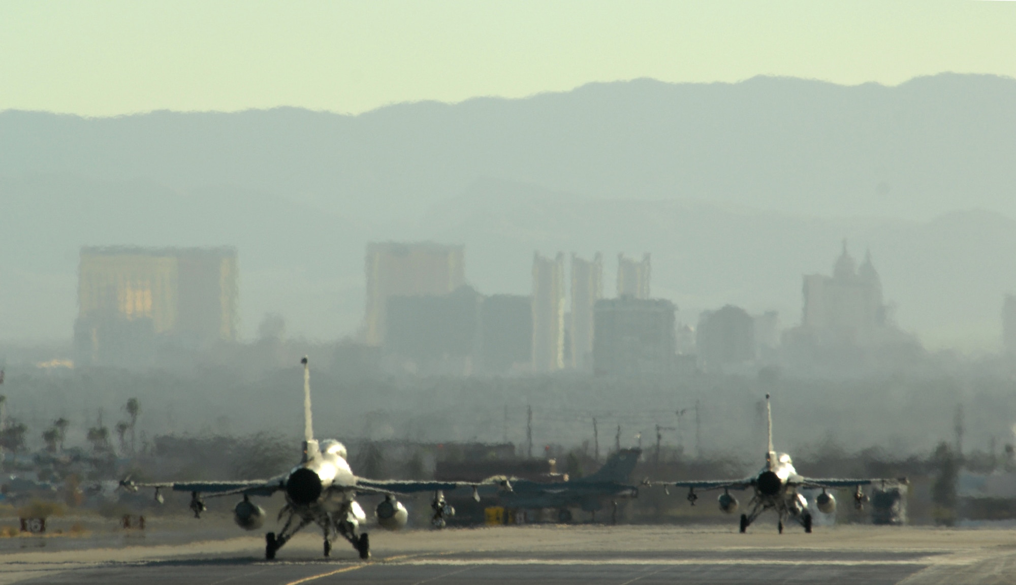 With the world famous Las Vegas Strip as the backdrop, two F-16 Fighting Falcons taxi out Oct. 18, 2007 at Nellis Air Force Base, Nev. The F-16’s are assigned to the 63rd Fighter Squadron, “The Panthers,” Luke AFB, Ariz. The 63rd FS is at Nellis supporting F-15 Eagles with the U.S Air Force Weapons School in an adversary tactics role.  (Air Force photo by Master Sgt. Kevin J. Gruenwald)



