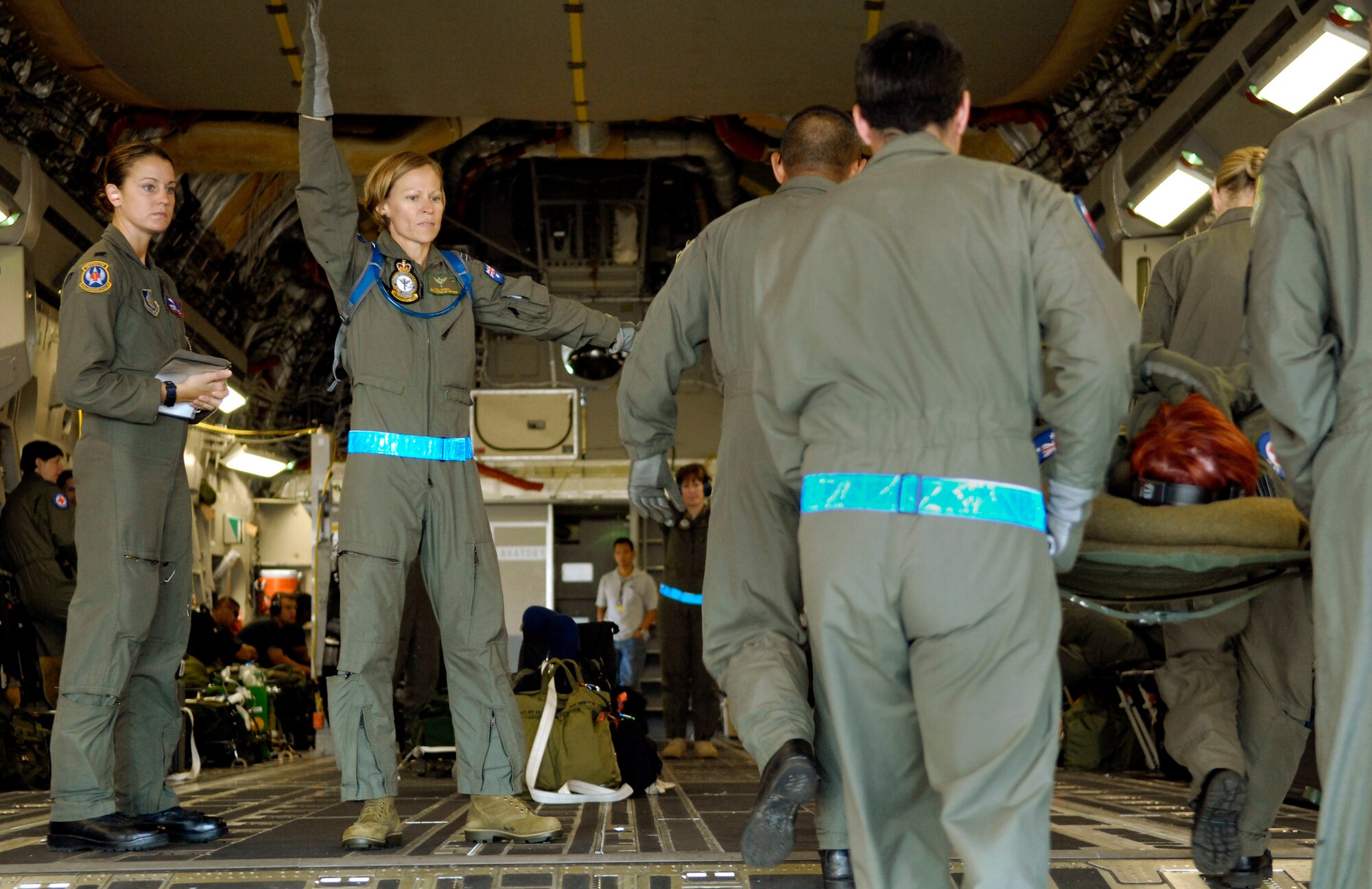 Capt. Jennifer Haubert observes as Royal Australian Air Force Fight Lt. Robyn Tatnell directs her team to load patients on a C-17 Globemaster III Oct. 16 during aeromedical evacuation operations training at Hickam Air Force Base, Hawaii. Airmen from the 18th Aeromedical Squadron at Kadena Air Base, Japan, are at Hickam to train RAAF medical personnel who will be using specialized equipment and the C-17 for aeromedical evacuation.  Captain Haubert is with the 18th AMS.  (U.S. Air Force photo/Tech. Sgt. Shane A. Cuomo) 