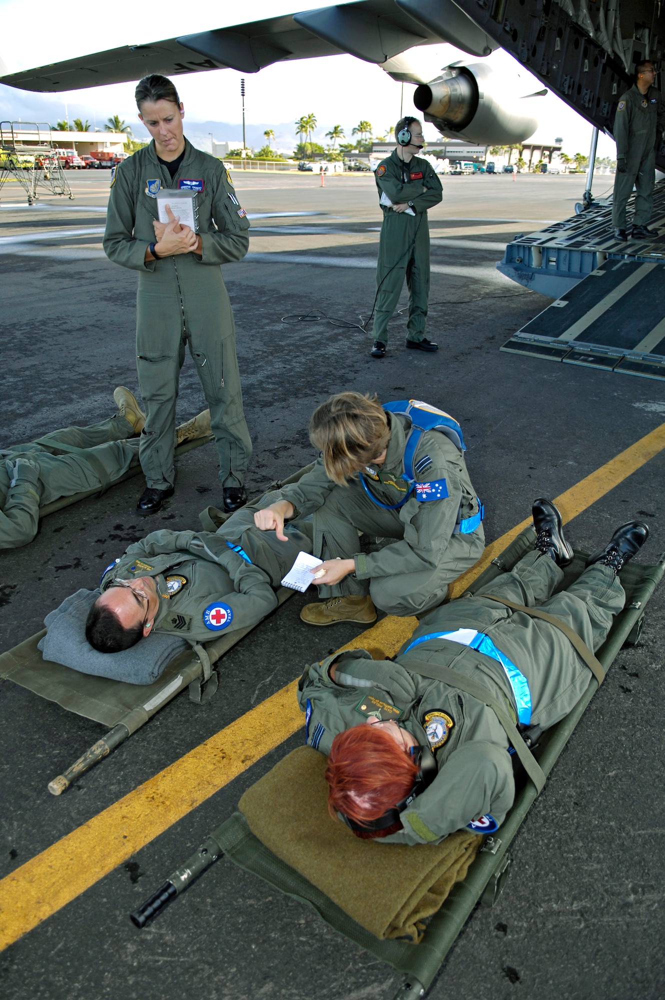 Capt. Jennifer Haubert observes as Royal Australian Air Force Fight Lt. Robyn Tatnell briefs litter patients before they are loaded on to a C-17 Globemaster III Oct. 16 during aeromedical evacuation operations training at Hickam Air Force Base, Hawaii.  Airmen from the 18th Aeromedical Squadron at Kadena Air Base, Japan, are at Hickam to train RAAF medical personnel who will be using specialized equipment and the C-17 for aeromedical evacuation.  Captain Haubert is with the 18th AMS.  (U.S. Air Force photo/Tech. Sgt. Shane A. Cuomo) 
