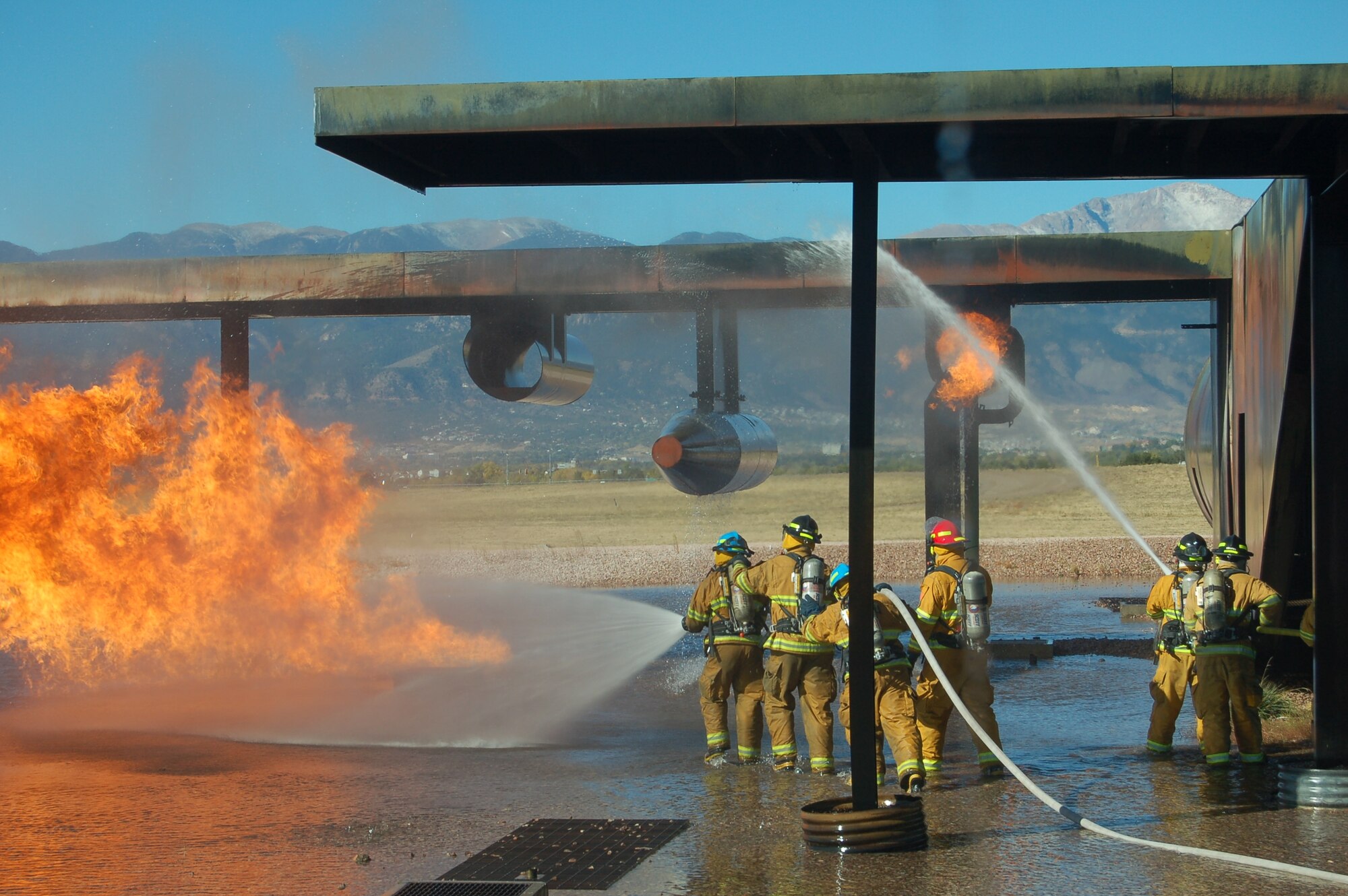 Peterson and Colorado Springs firefighters work to extinguish a fire at the base’s fire training site. The two departments held a joint exercise Oct. 18 and 19 to improve their teamwork skills. (U.S. Air Force photo by Corey Dahl) 