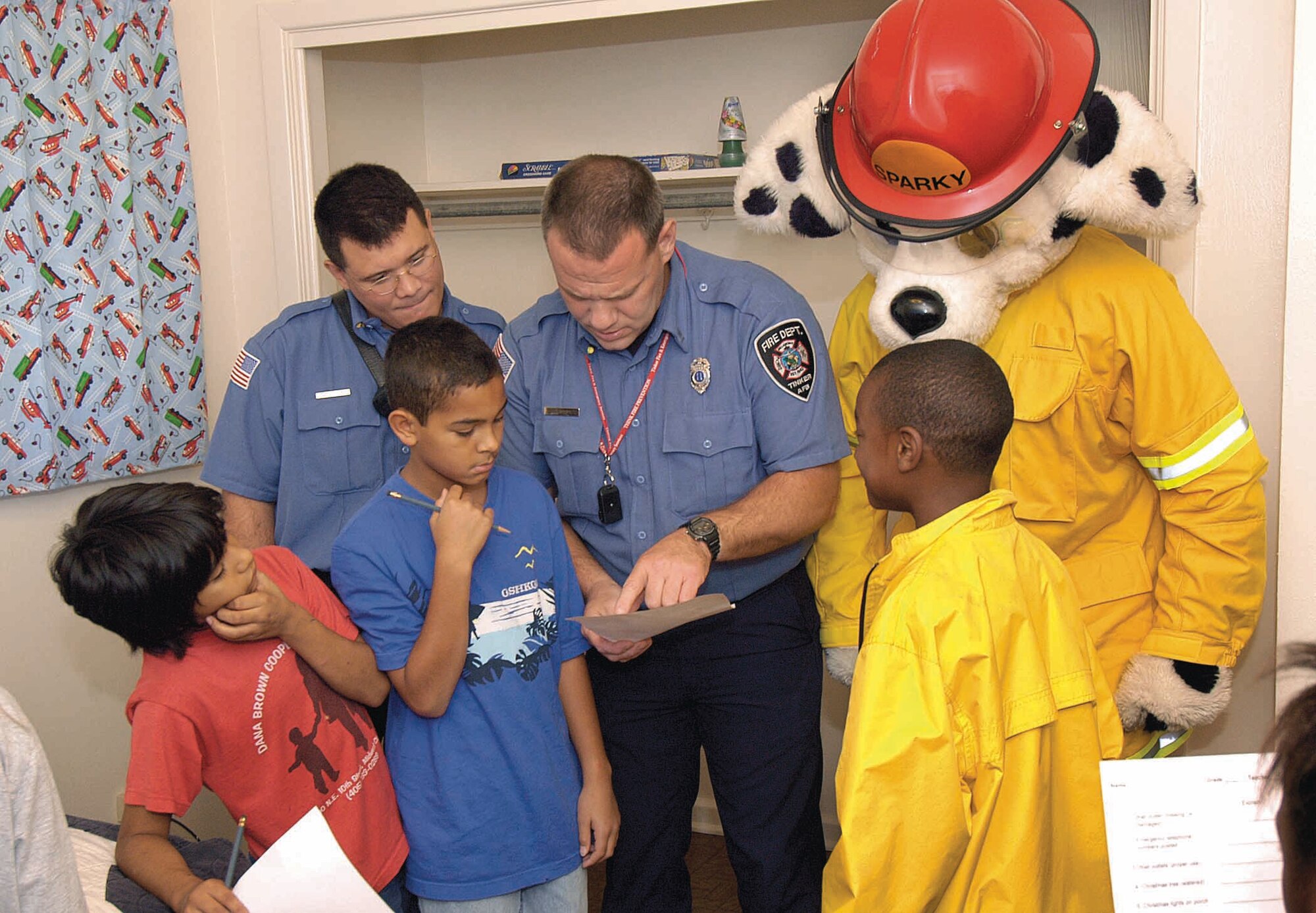 In the new 72nd Air Base Wing Fire Safety House, or "Spark's House," students hunted for fire hazards like overloaded outlets, clothes draped over lamps and curling irons on beds. Firefighters go over Tinker fifth-graders' checklists of found hazards. (Air Force photo by Margo Wright)