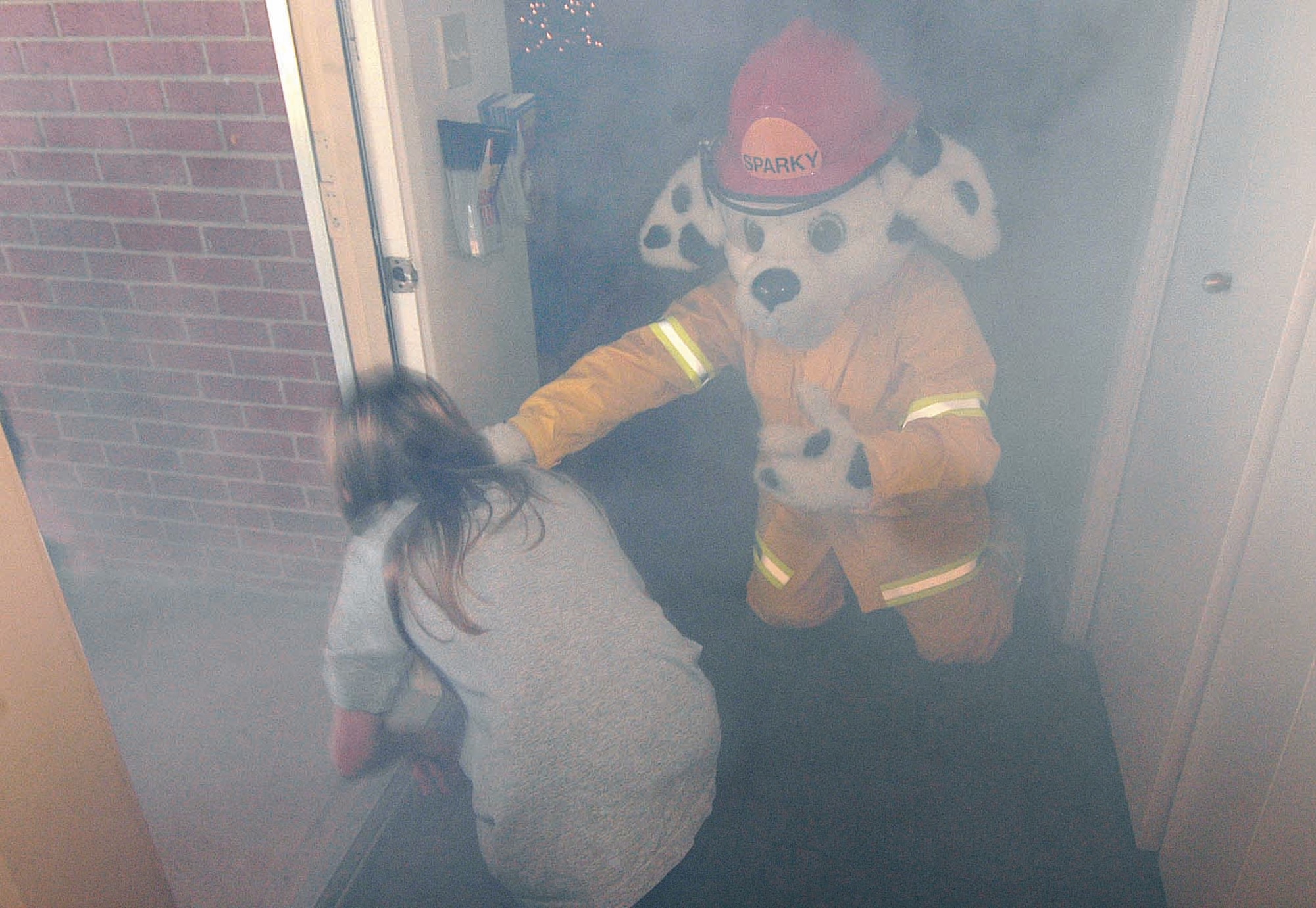 Under the watchful eye of Tinker Fire Department mascot Sparky, Tinker Elementary School 5th-graders practice staying low and crawling through smoke to the front door of “Sparky’s House”. The base housing home is now used to educate kids and adults on fire safety. (Air Force photo by Margo Wright)