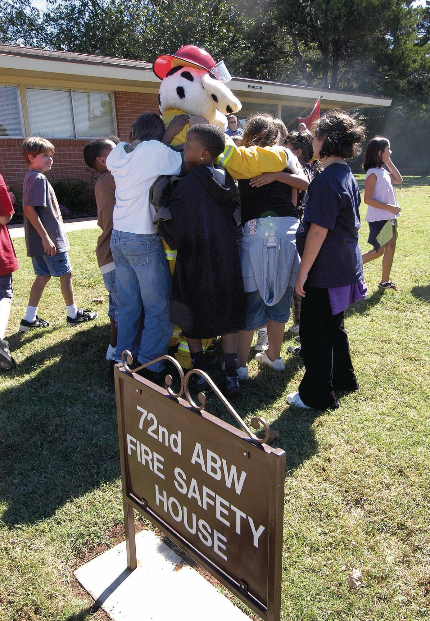 Tinker Elementary School fifth-graders group hug Sparky, the Tinker Fire Department mascot, outside "Sparky's House" after exercises in fire safety. Students looked for unsafe things, watched videos and learned how to escape a home filled with smoke. (Air Force photo by Margo Wright)