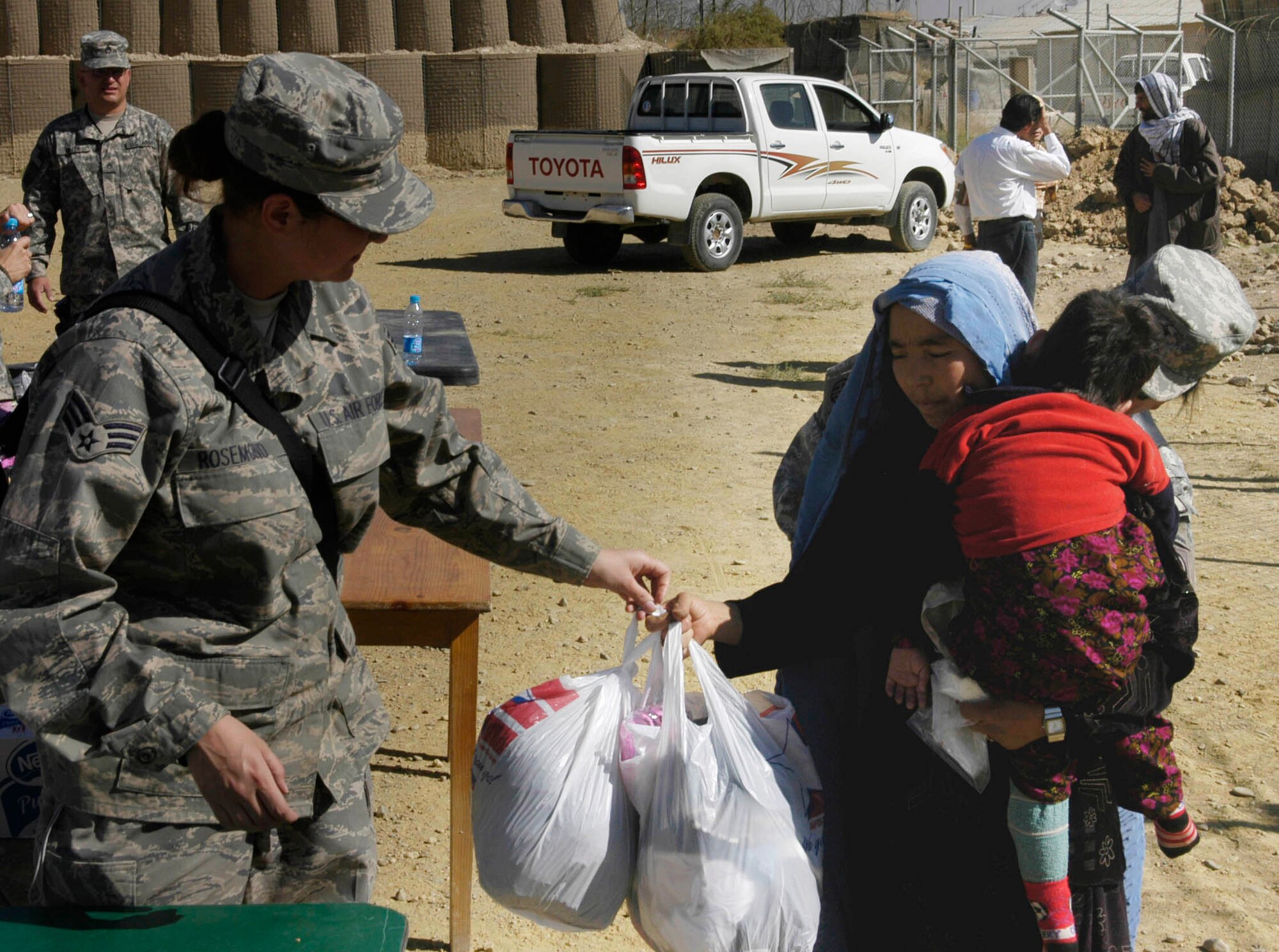 Senior Airman Elisa Rosemond pass out bags of clothes to Afghan mother and her child during an Operation Care visit to the Korean Hospital Oct. 17 near Bagram Air Base, Afghanistan. Operation Care is an all-volunteer effort that provides clothes, school and hygiene supplies, toys and candy to Afghan villagers. (U.S. Air Force photo/Capt. Michael Meridith)